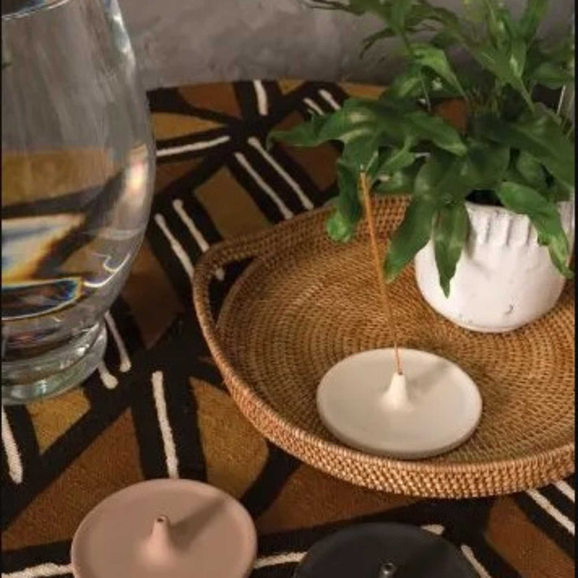 Potted green plant in a white container beside candles and a glass vase