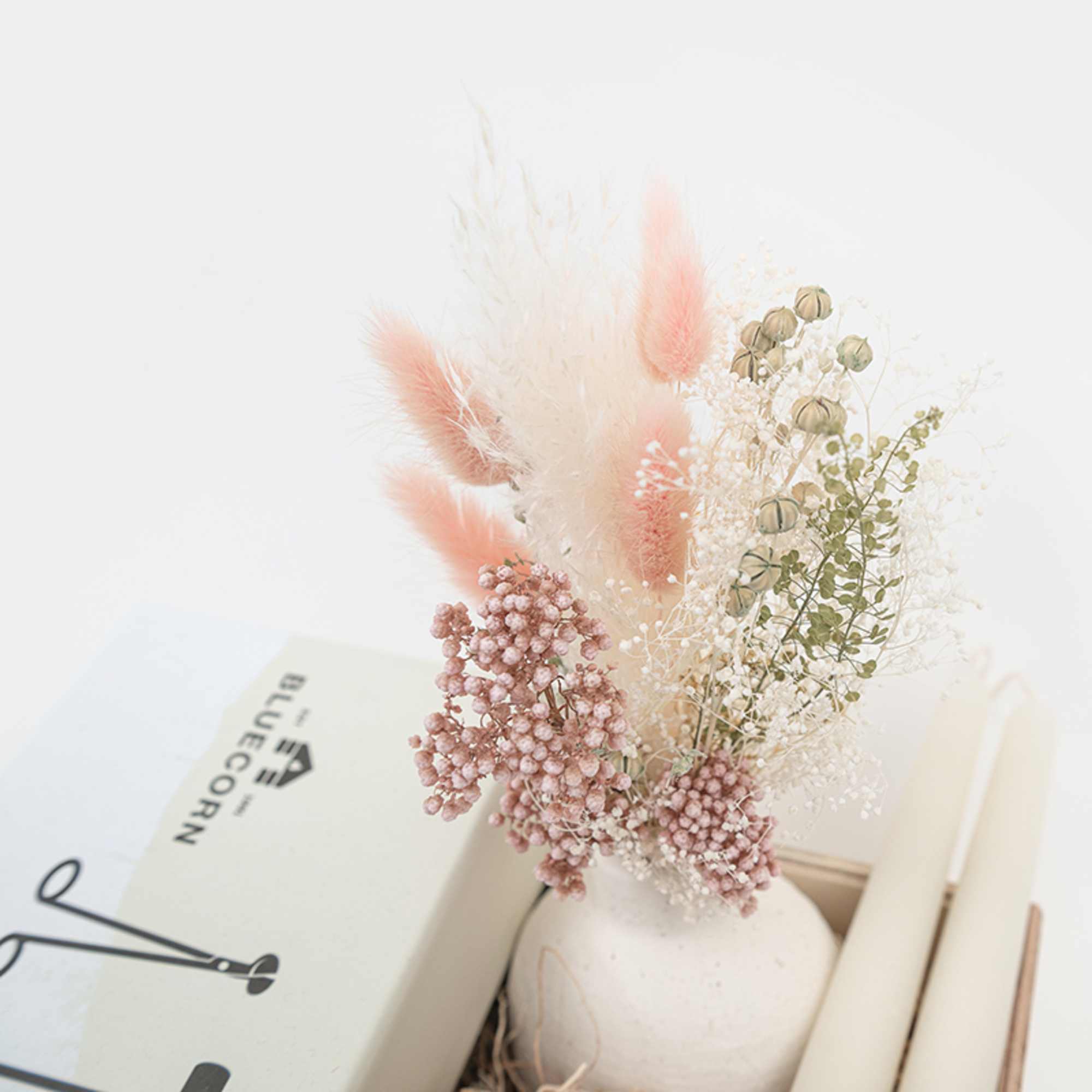 Dried floral arrangement in a white vase with pink and cream accents
