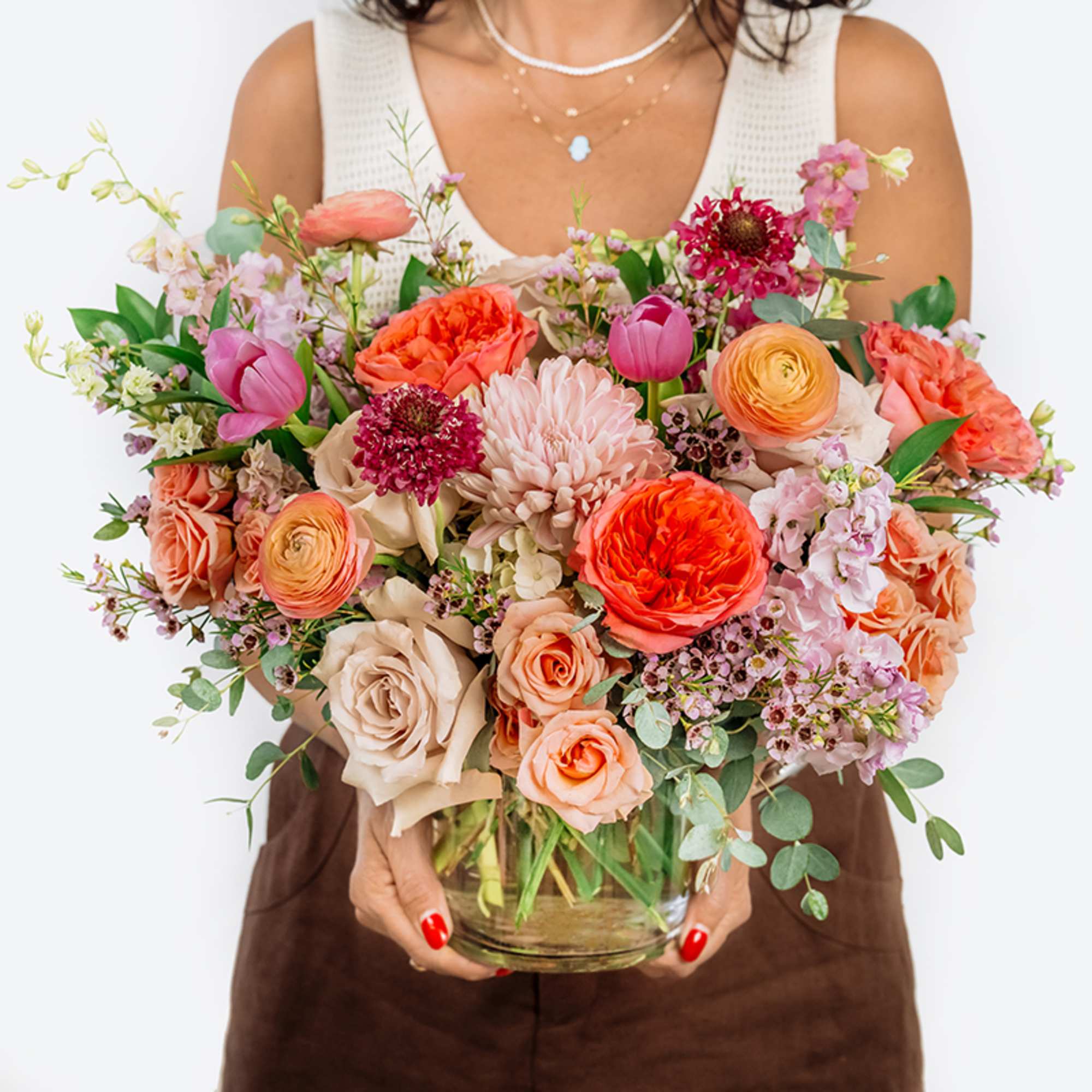 Large mixed bouquet of peach, pink, and coral flowers in a glass vase