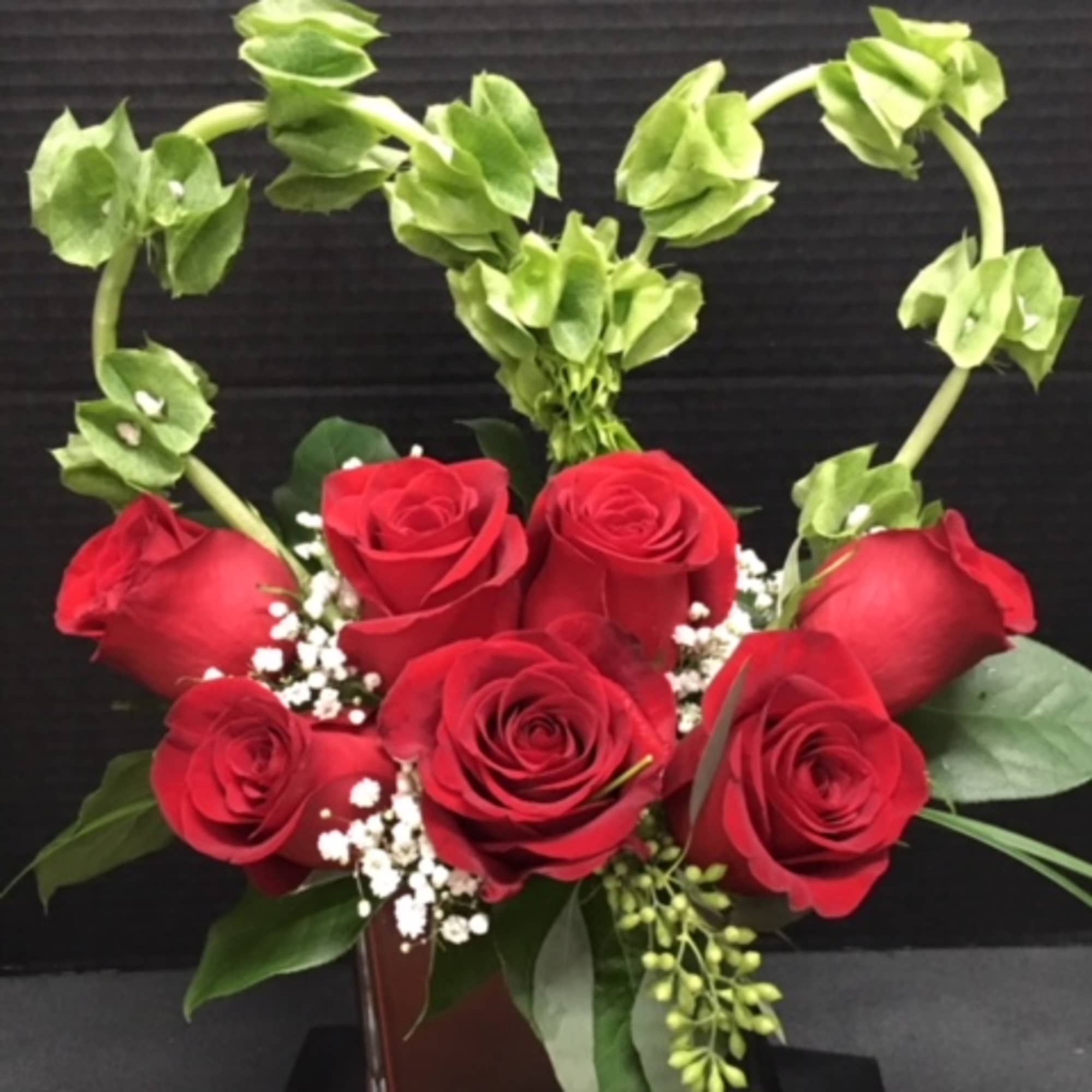 Red roses in a square glass vase with arched green stems