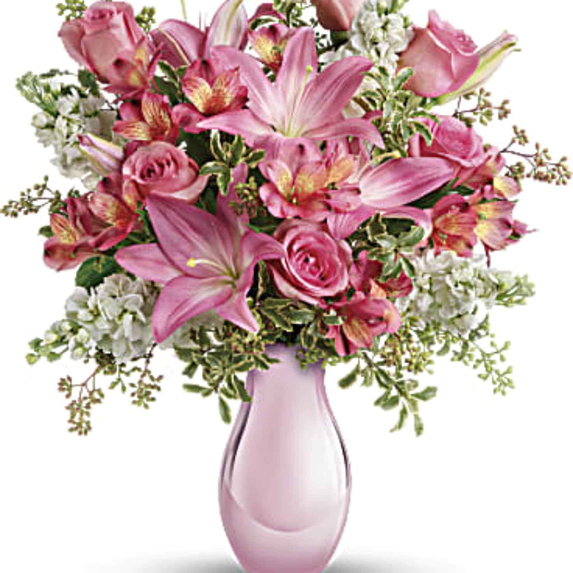 Pink lilies, roses, and white filler flowers in a pink vase