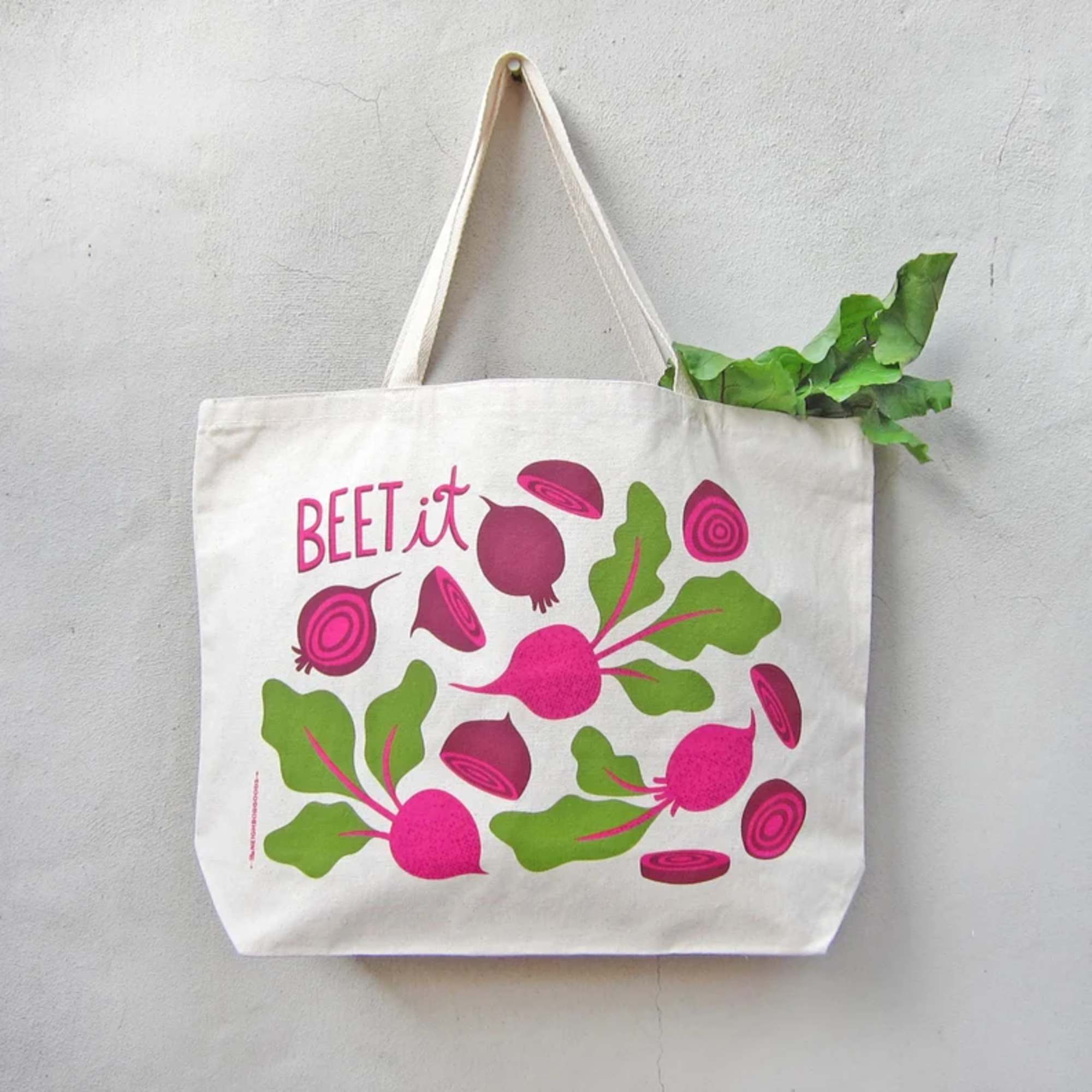 Cream canvas tote bag with pink and green beet illustrations and the words “BEET it”.
