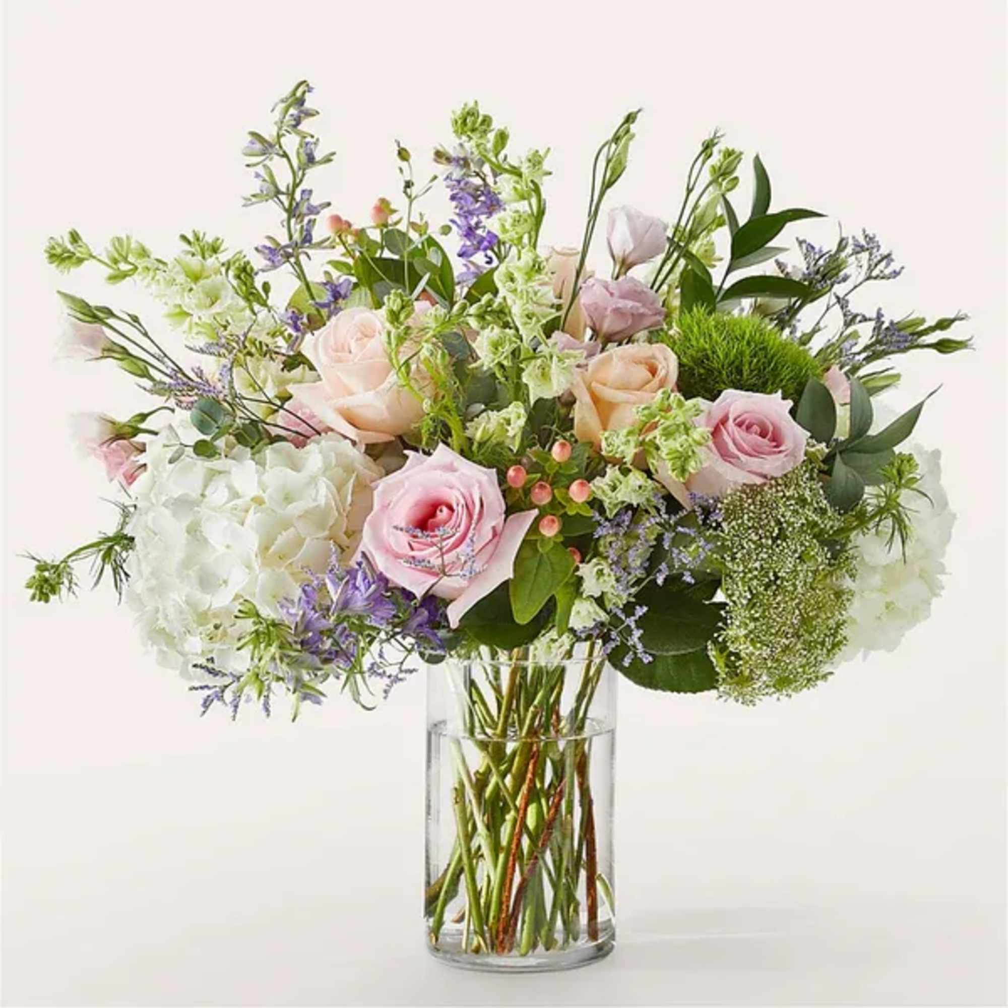 Pastel bouquet of pink roses, white hydrangeas, and mixed blooms in a clear glass vase