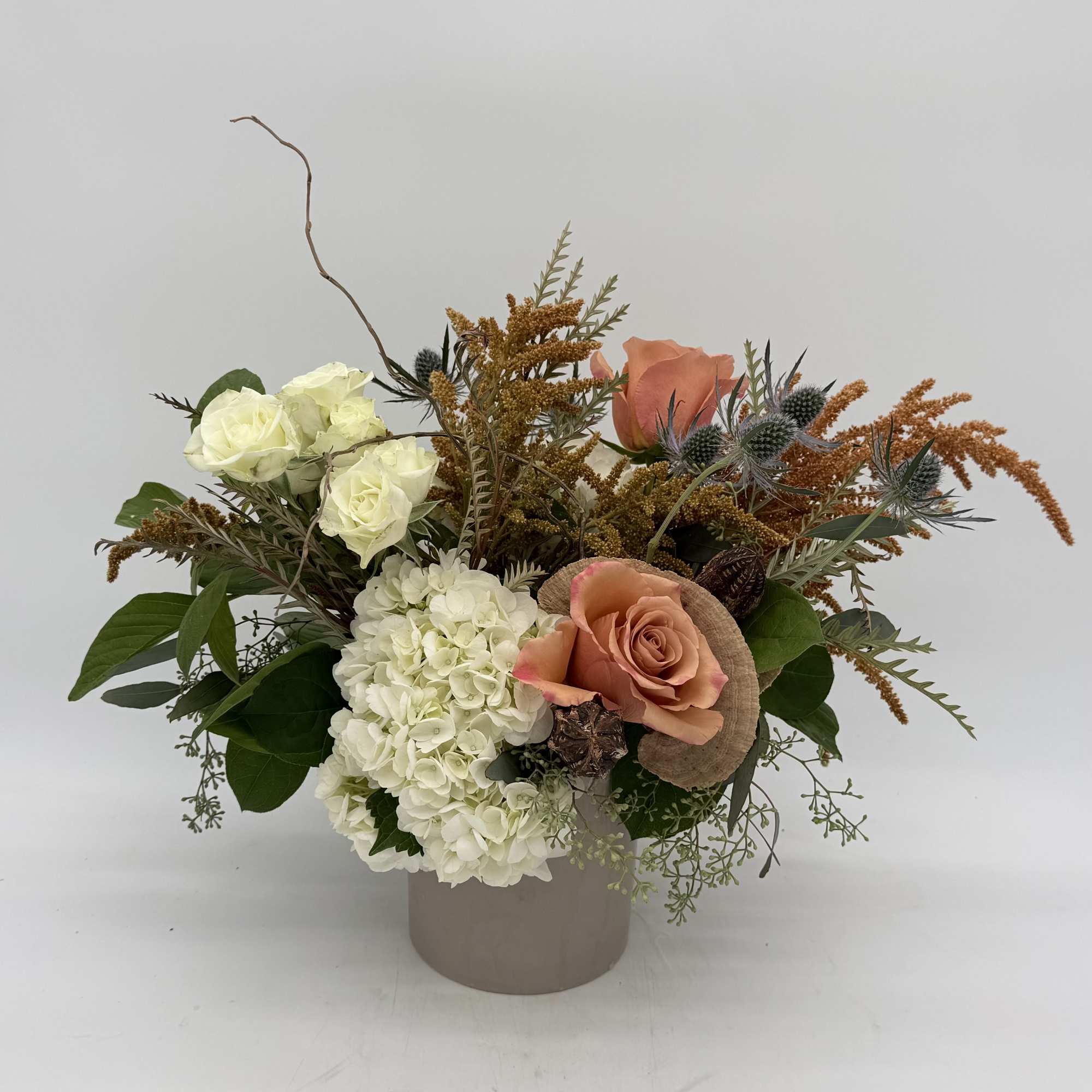 Mixed bouquet in a beige vase with white hydrangea and peach roses