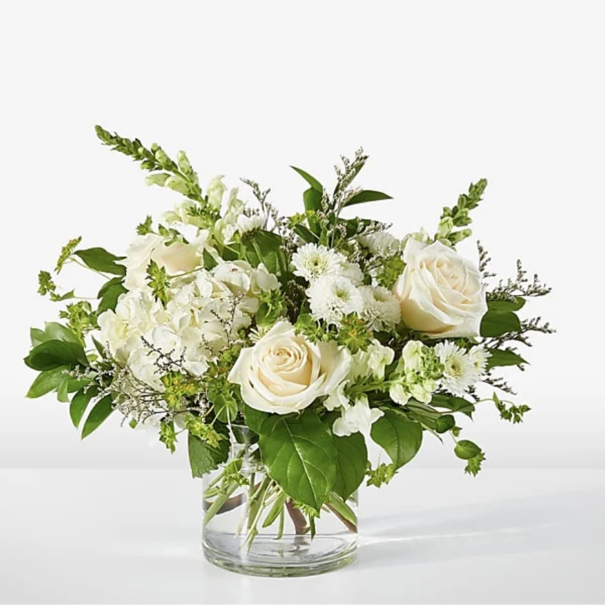White roses and mixed white flowers in a clear glass vase