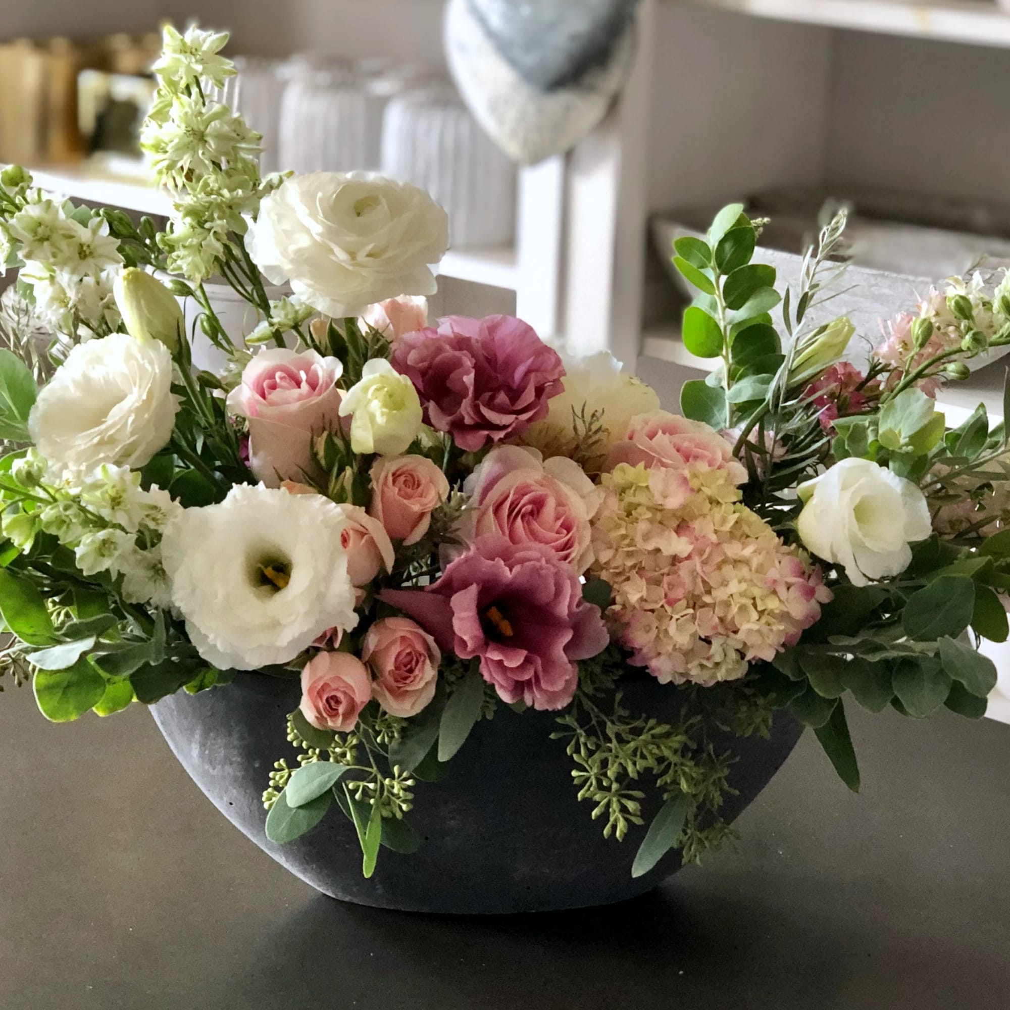Low floral arrangement with pink and white blooms in a dark bowl vase