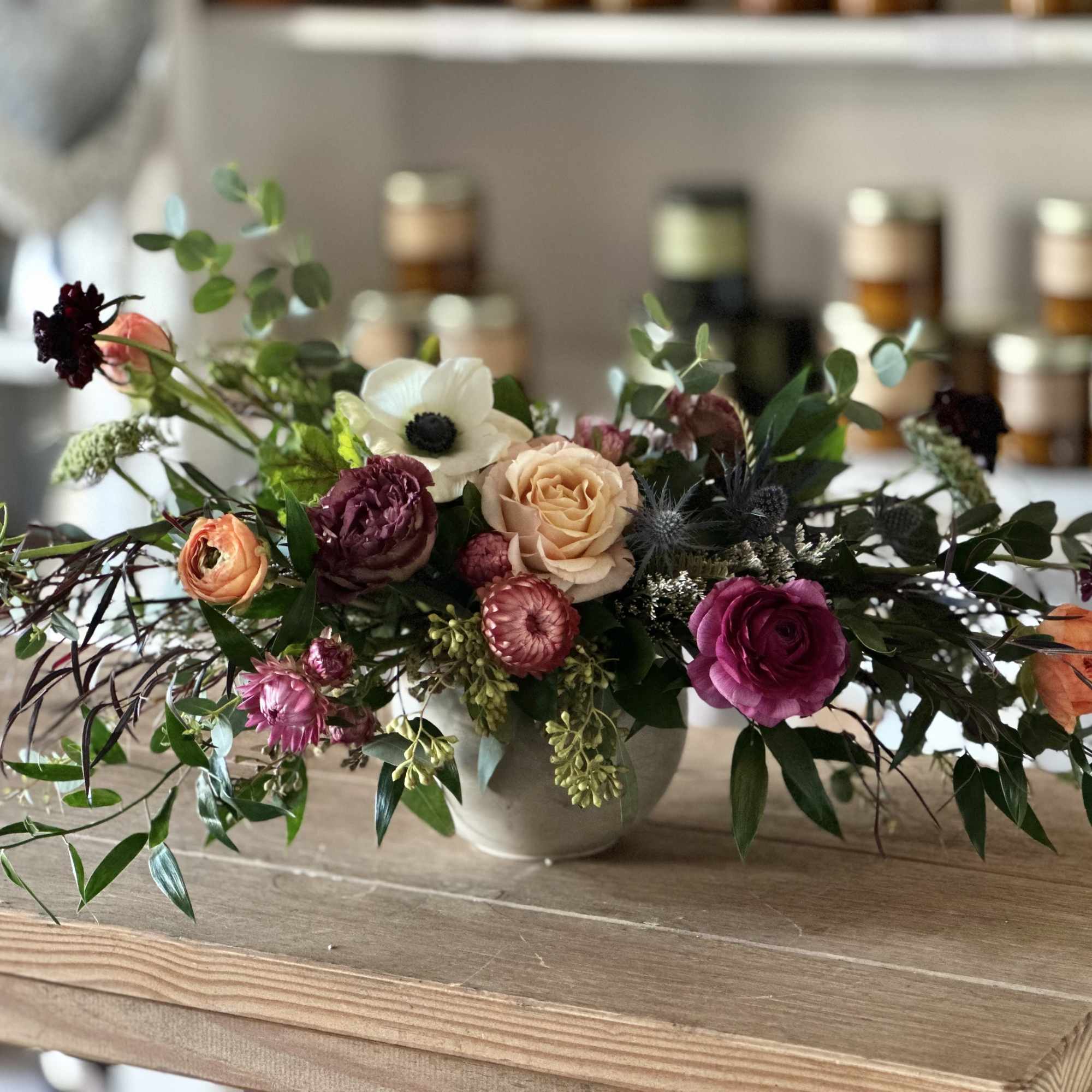 Low floral arrangement in a ceramic vase with pink, peach, and white blooms
