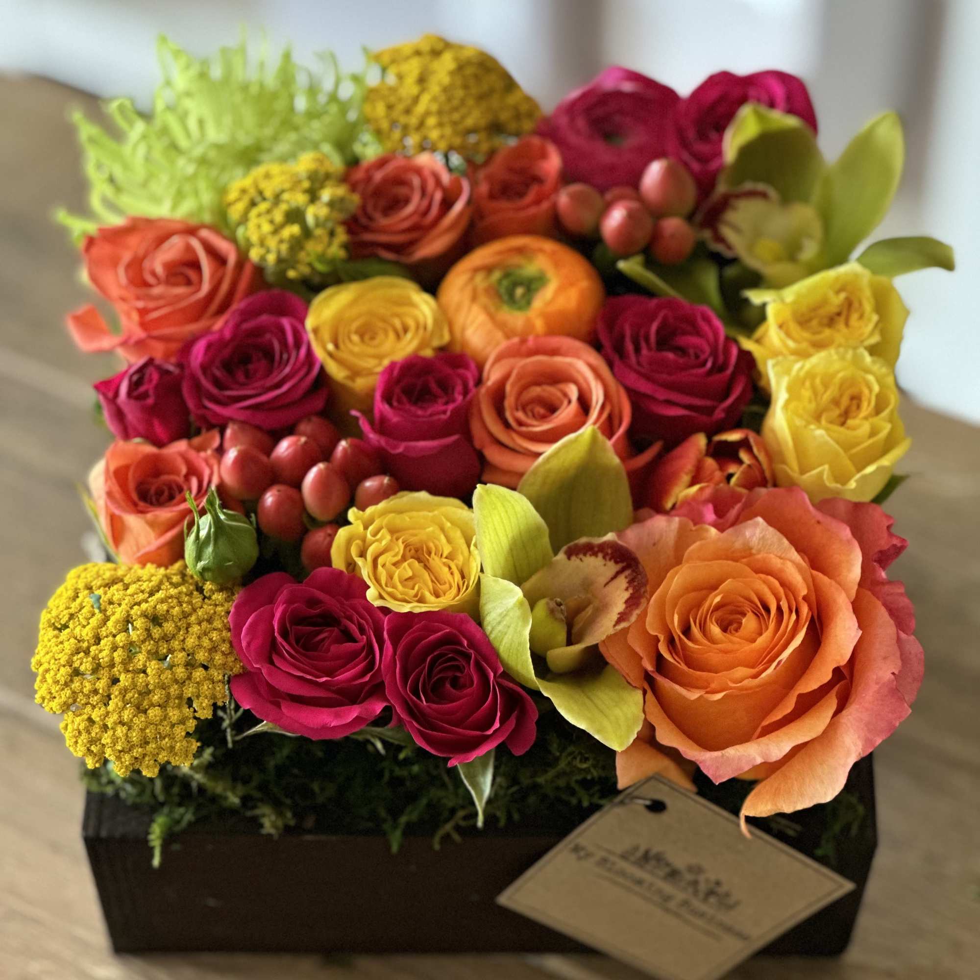 Colorful rose arrangement in a black box with yellow filler flowers