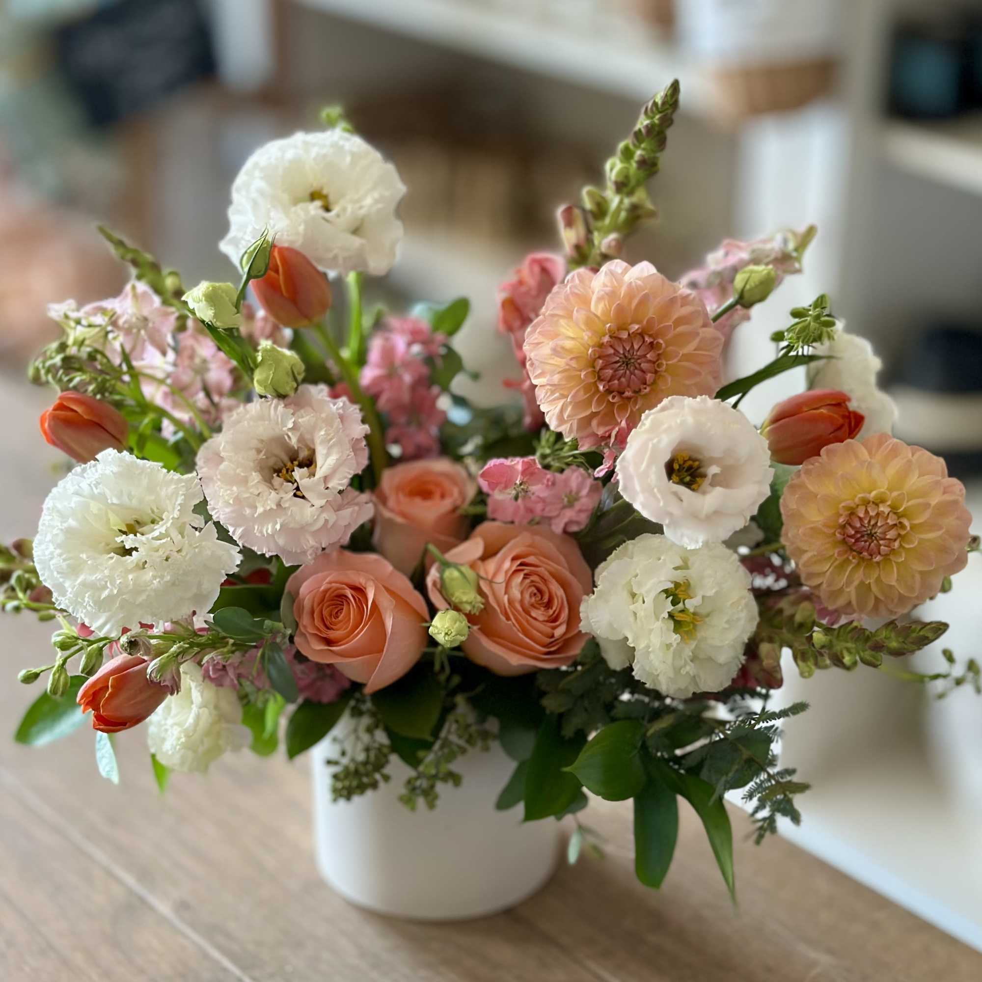 Peach and white floral arrangement in a white vase