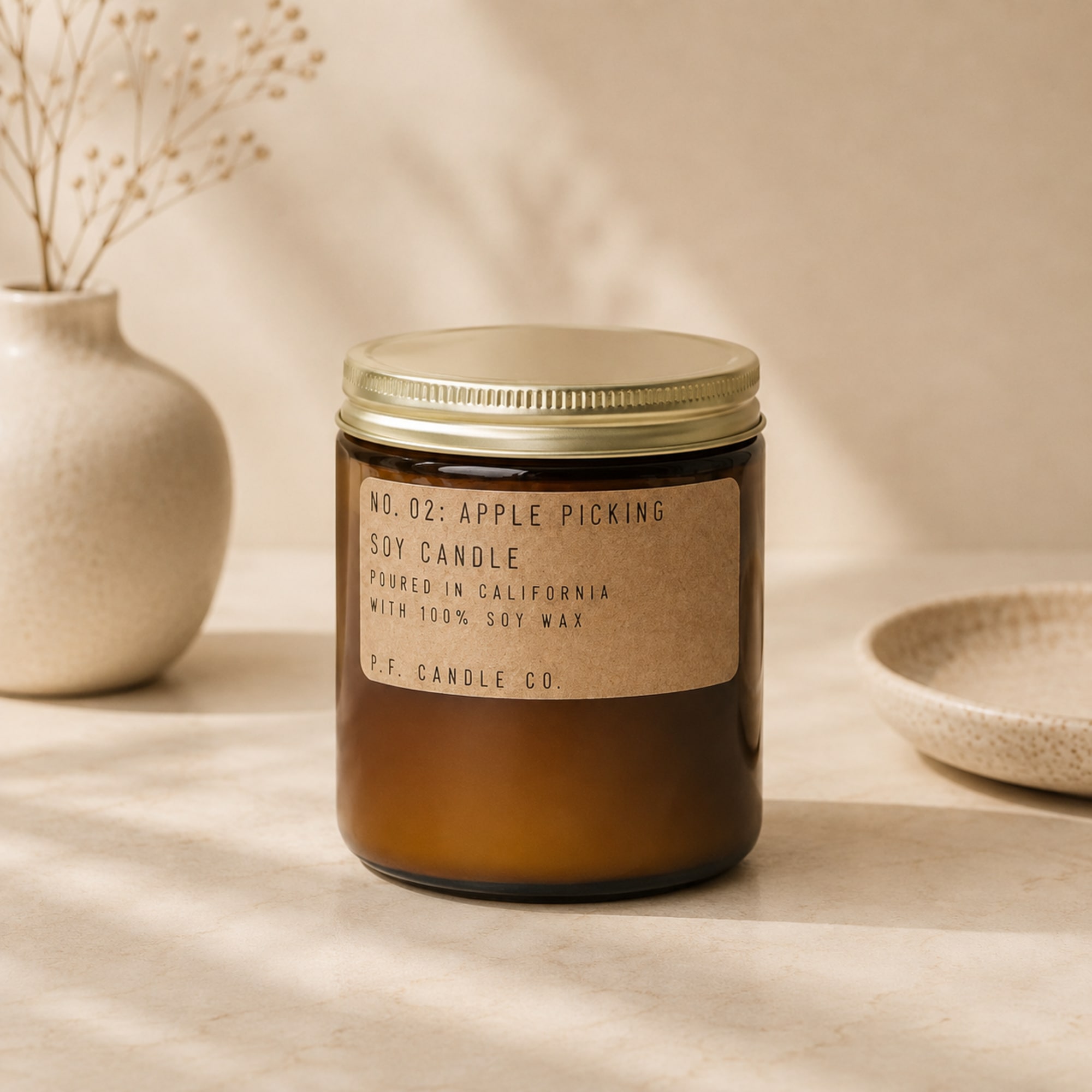 Amber jar candle with a gold lid and paper label
