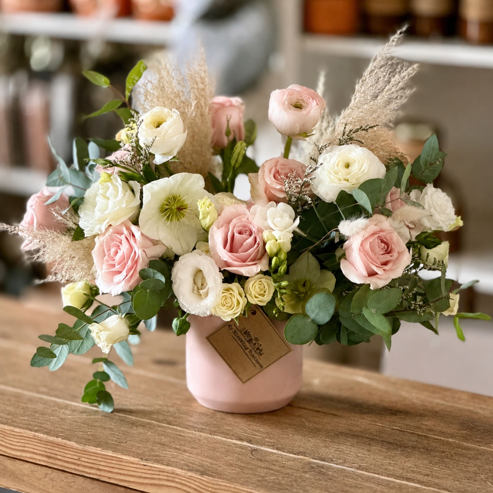 Pink and white roses in a blush vase with airy dried grasses