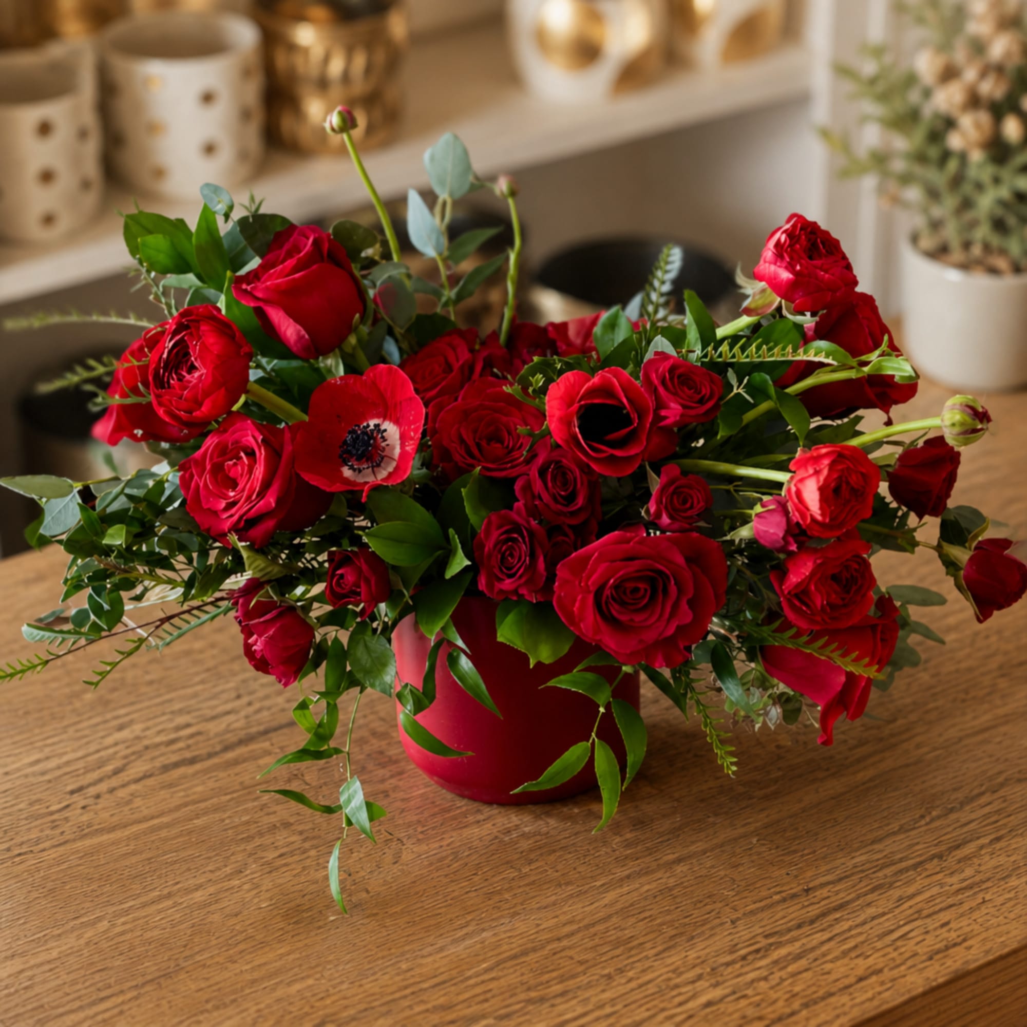 Red rose bouquet in a red vase with one red anemone