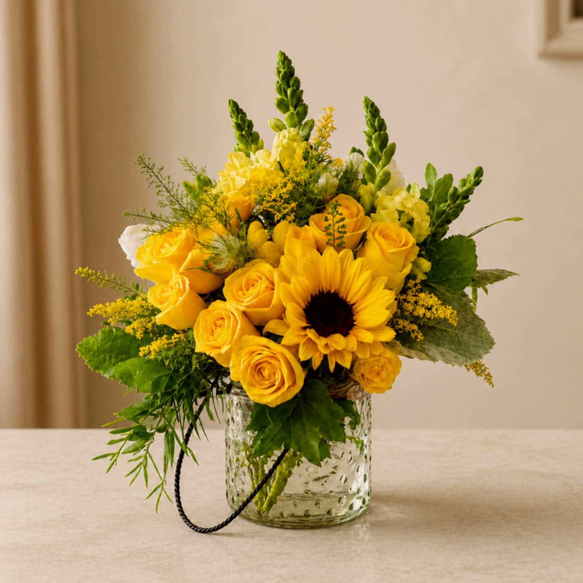 Yellow roses and a sunflower arranged in a clear glass vase