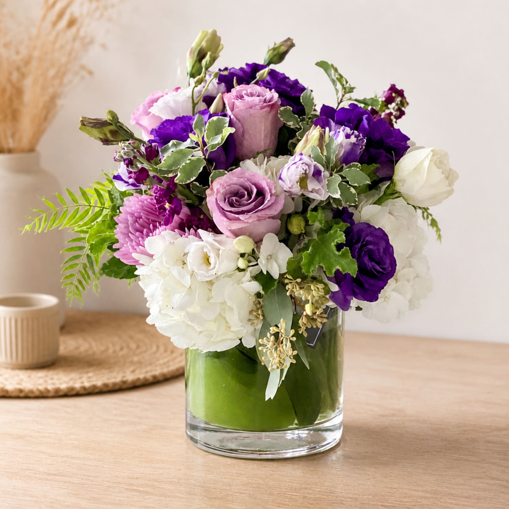 Purple and white mixed bouquet in a clear glass vase