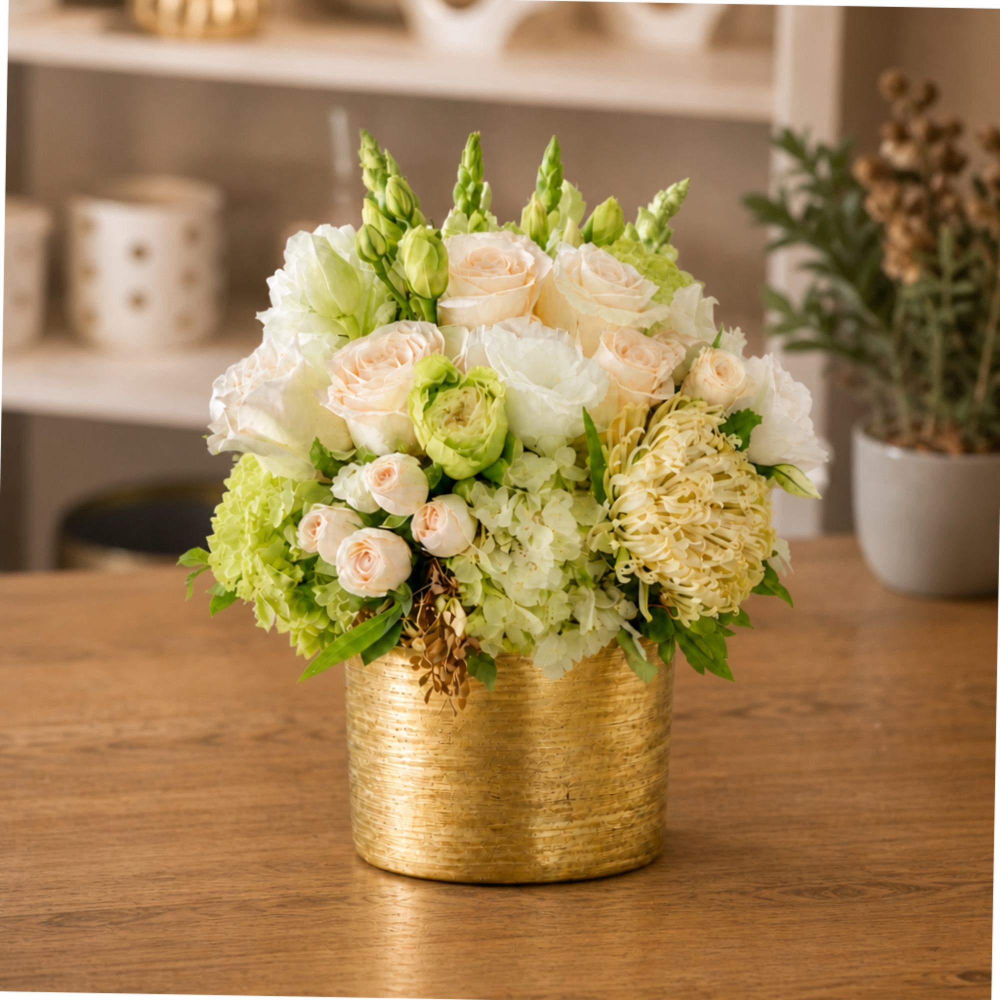 White and pale green floral arrangement in a gold container