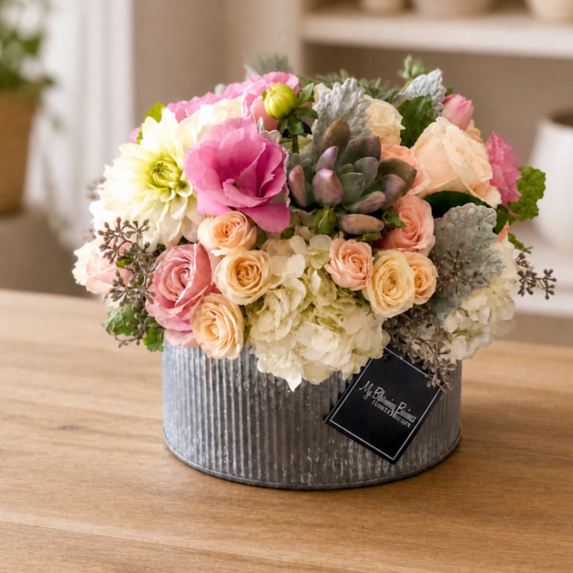 Mixed pink and cream flowers arranged in a ribbed metal container