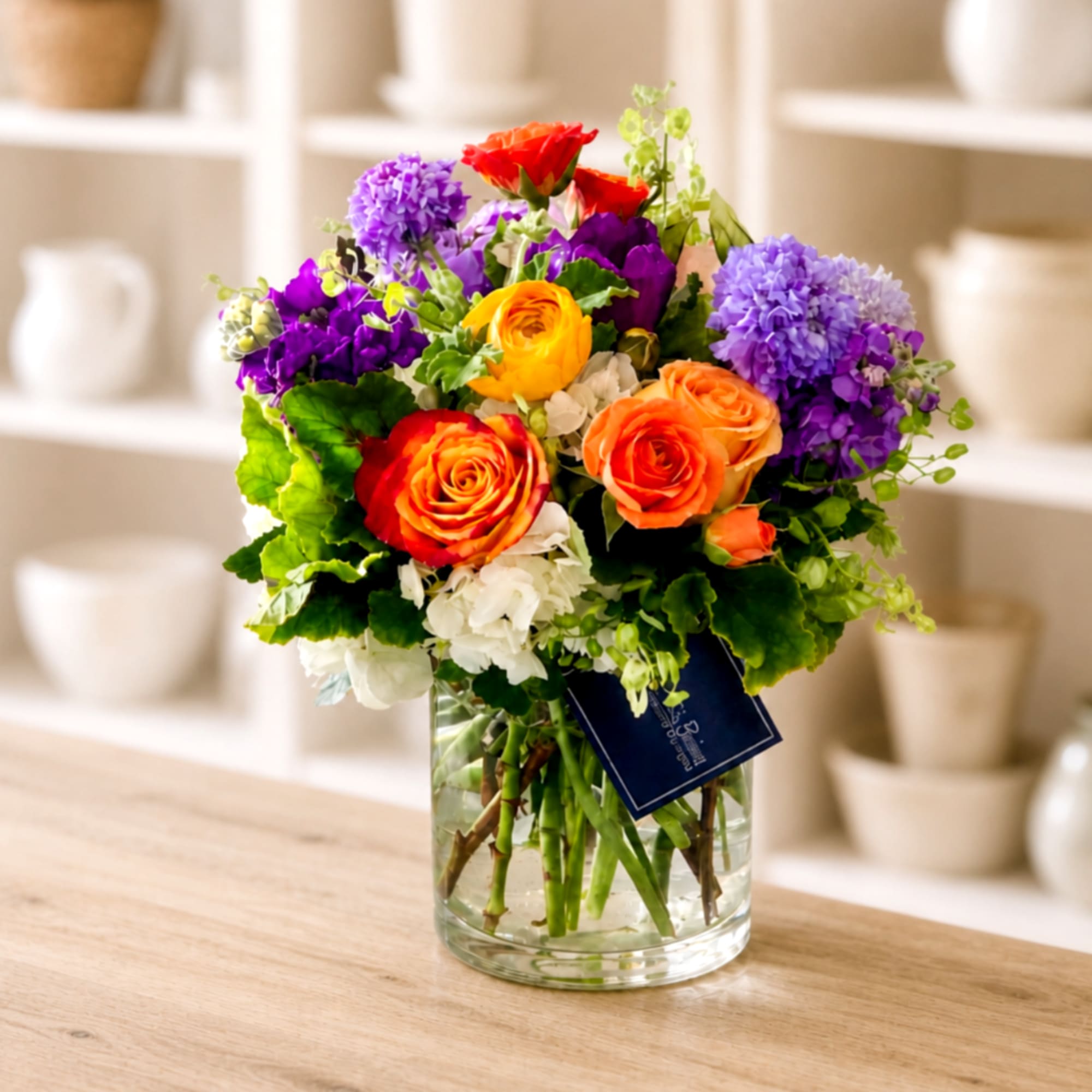 Colorful bouquet of roses and purple flowers in a clear glass vase