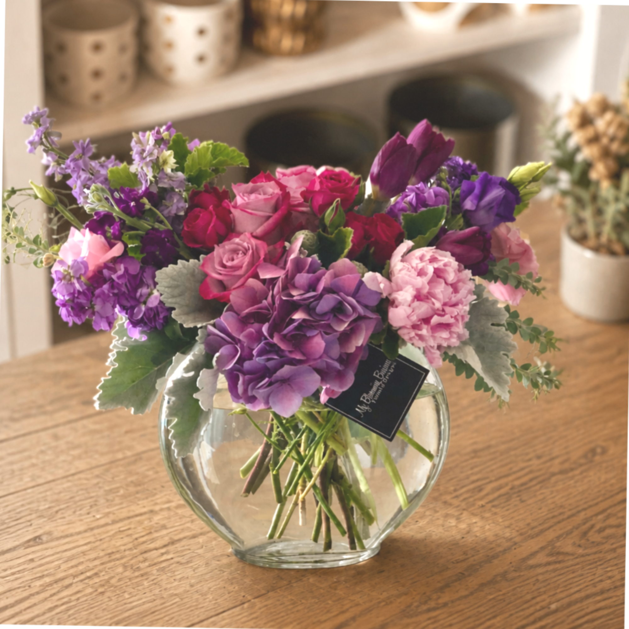 Mixed pink and purple flowers arranged in a clear glass vase