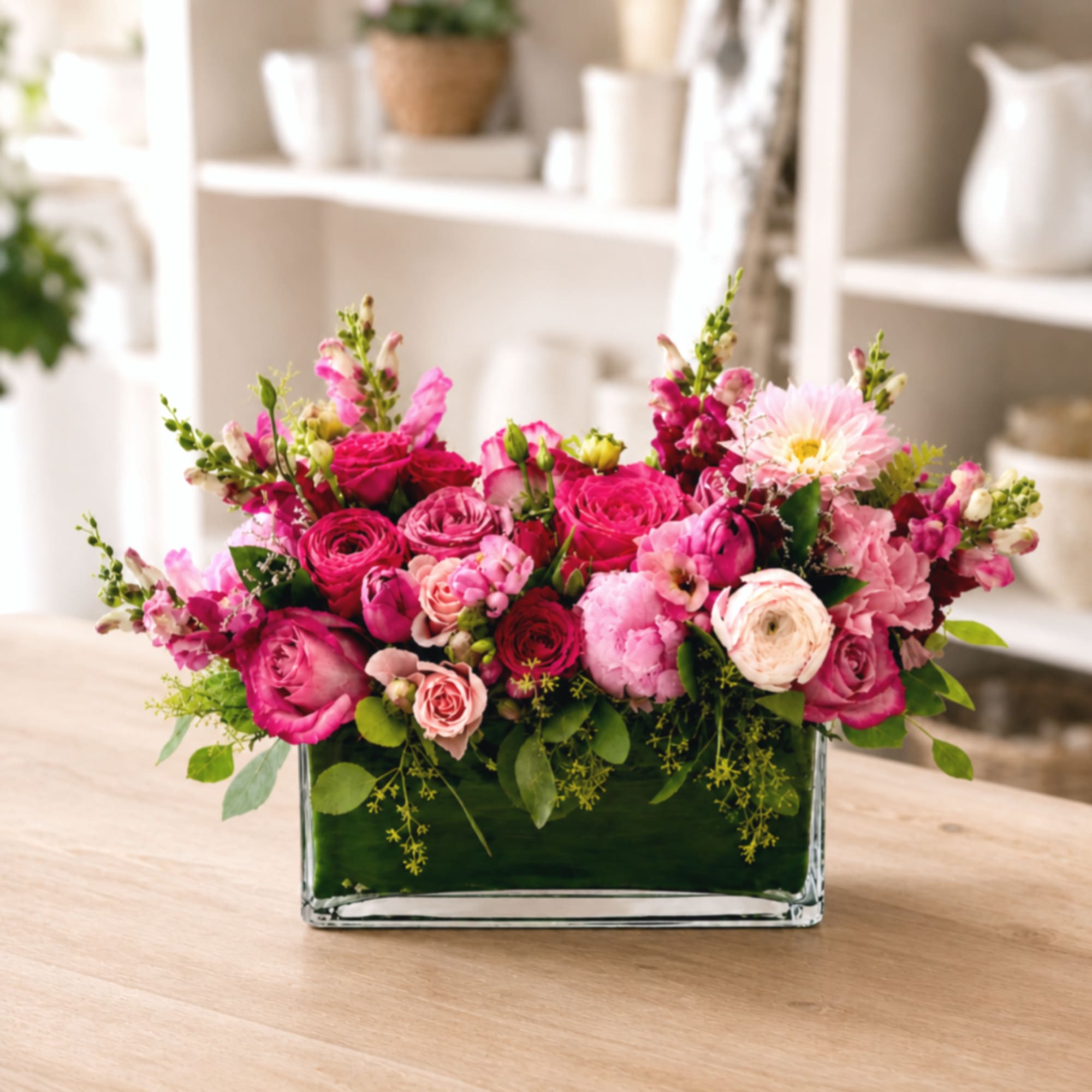 Pink mixed flower arrangement in a rectangular glass vase