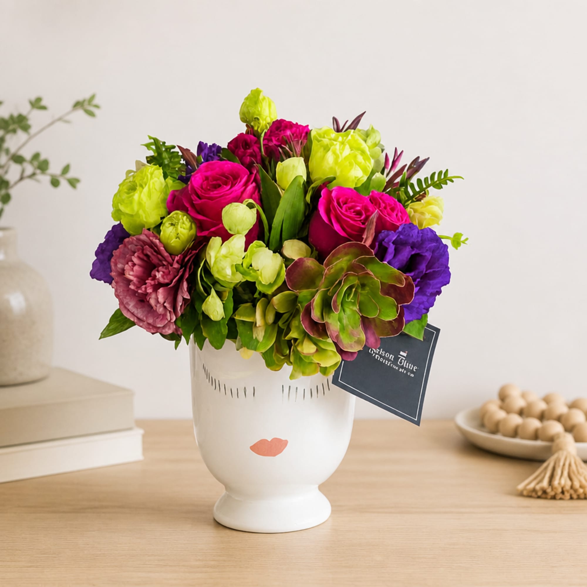 Bright mixed bouquet in a white vase with pink, purple, and green blooms