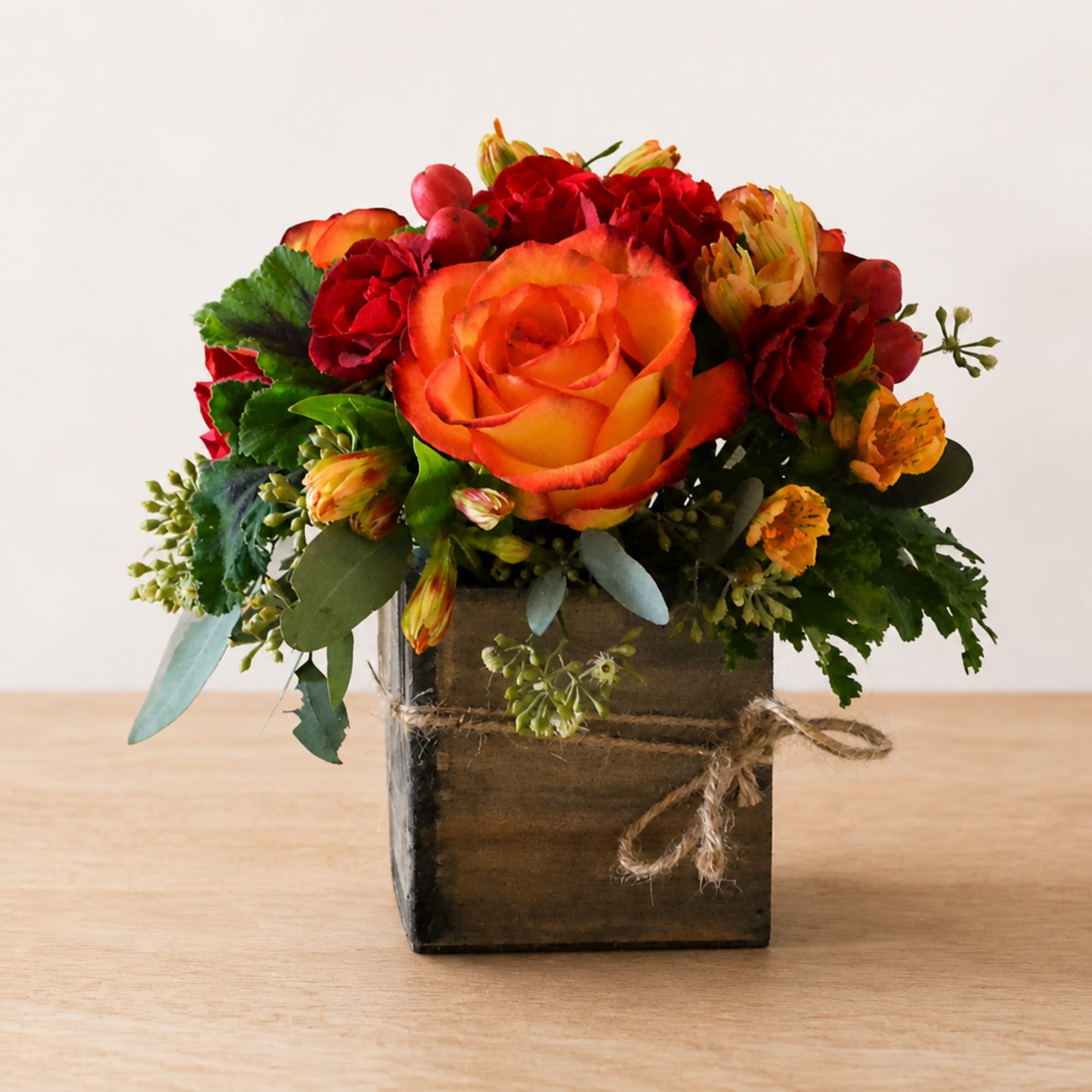 Orange and red floral arrangement in a rustic wooden box