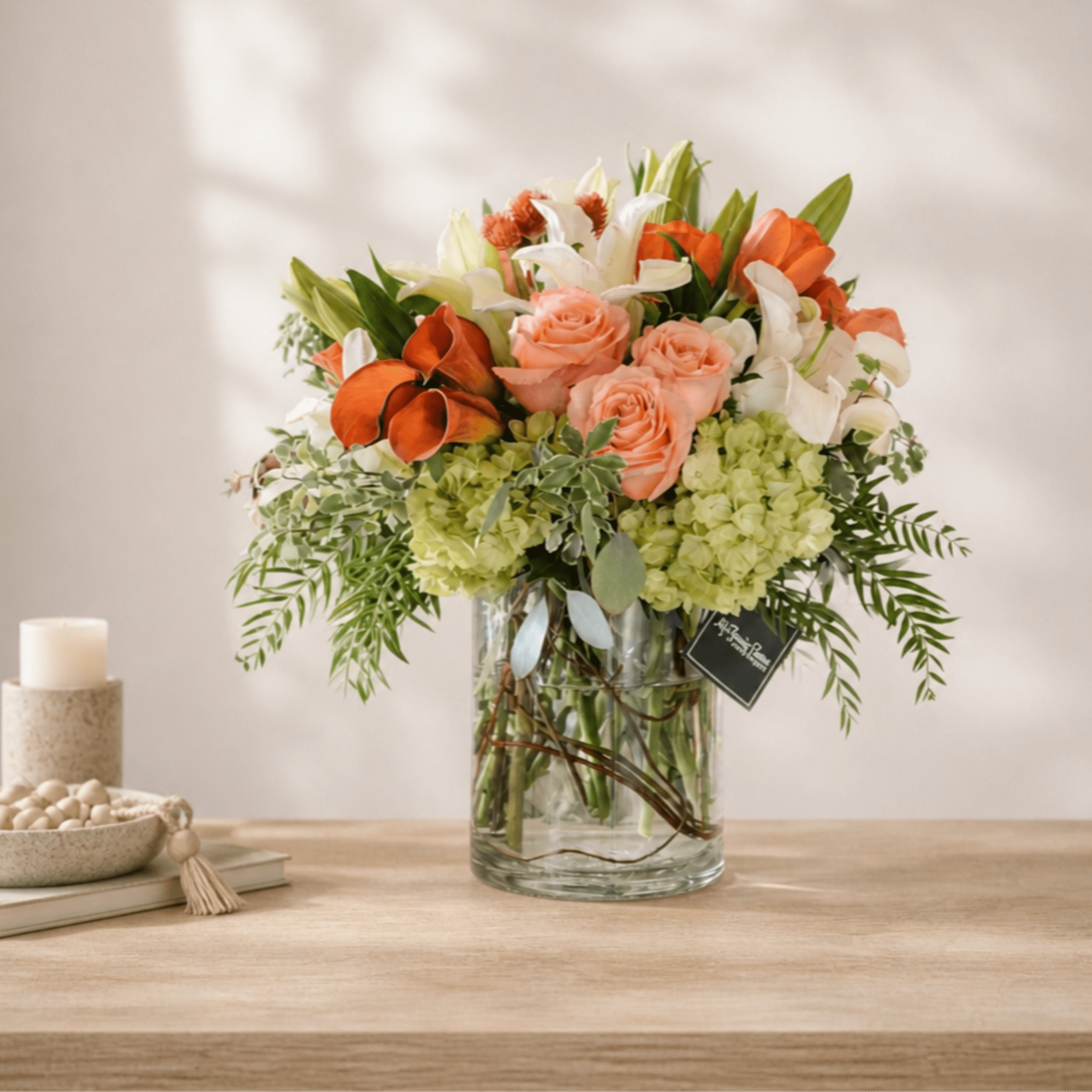 Orange and peach flowers in a clear glass vase with white blooms