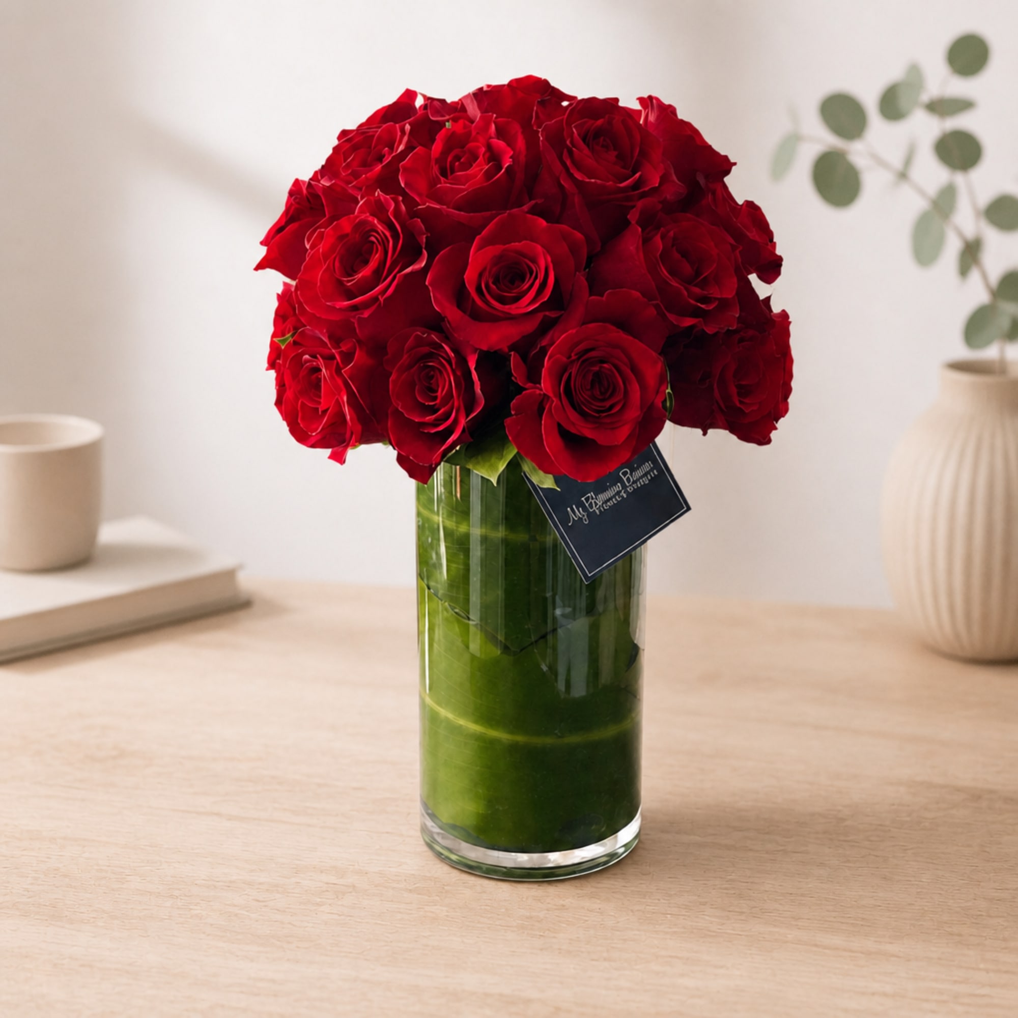 Red roses arranged in a clear glass vase on a tabletop