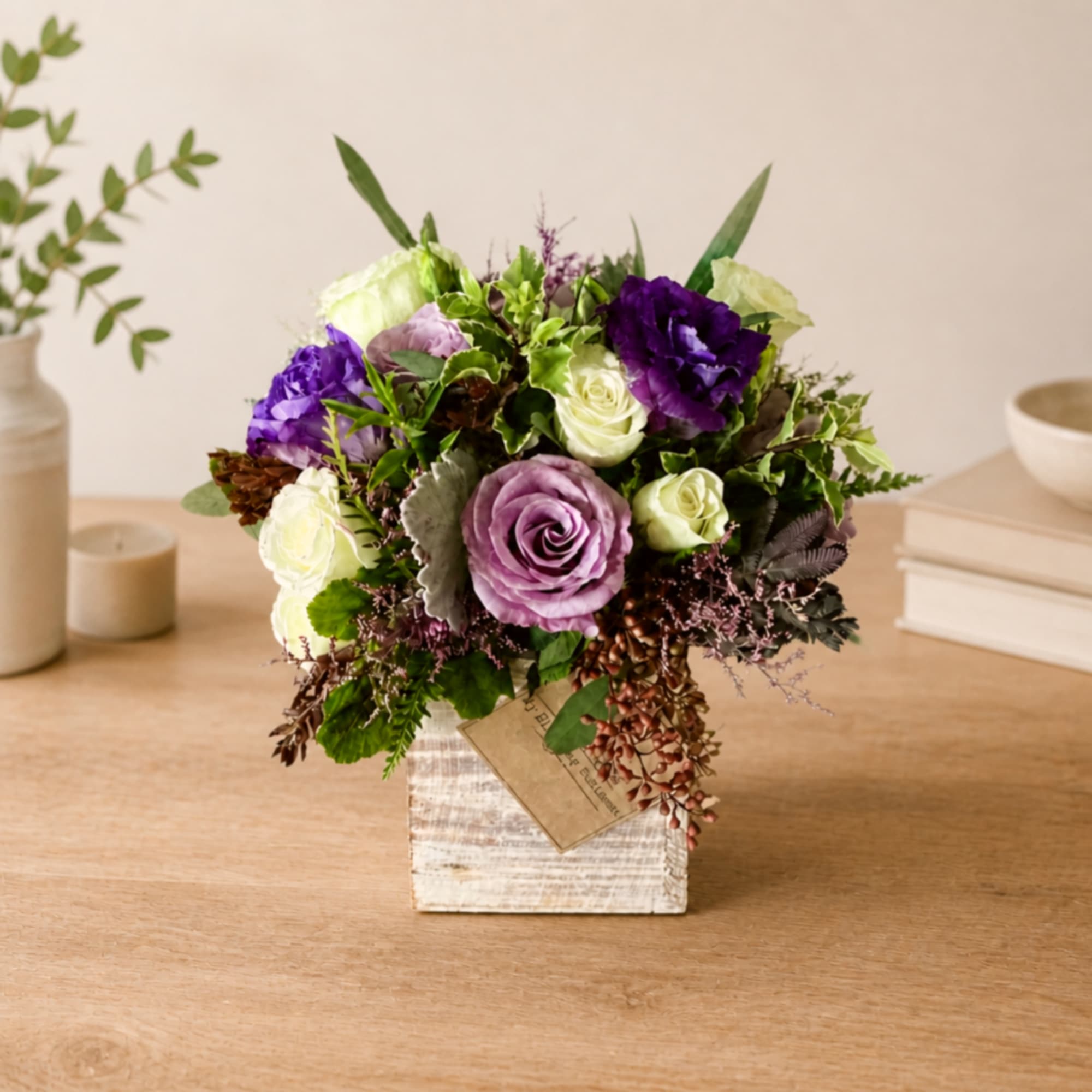 Purple and white rose arrangement in a rustic square container