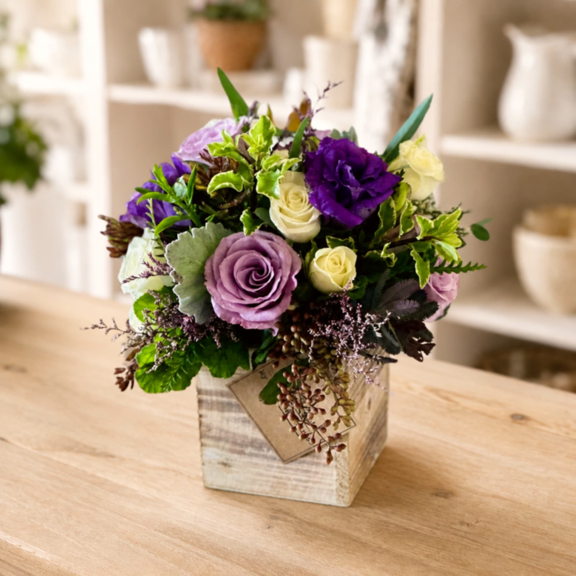 Purple and cream rose arrangement in a rustic wooden box