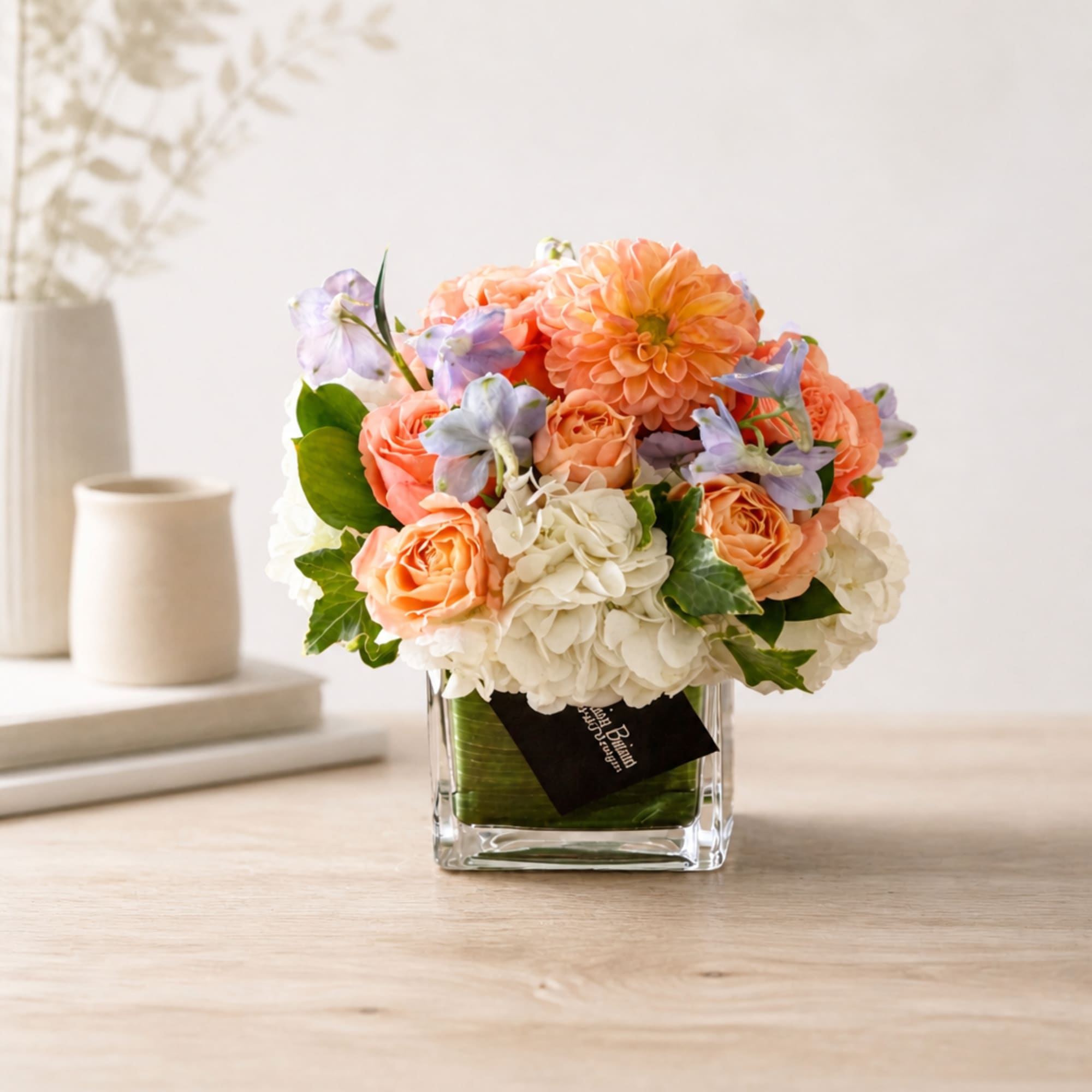 Peach roses and white hydrangeas in a clear square vase