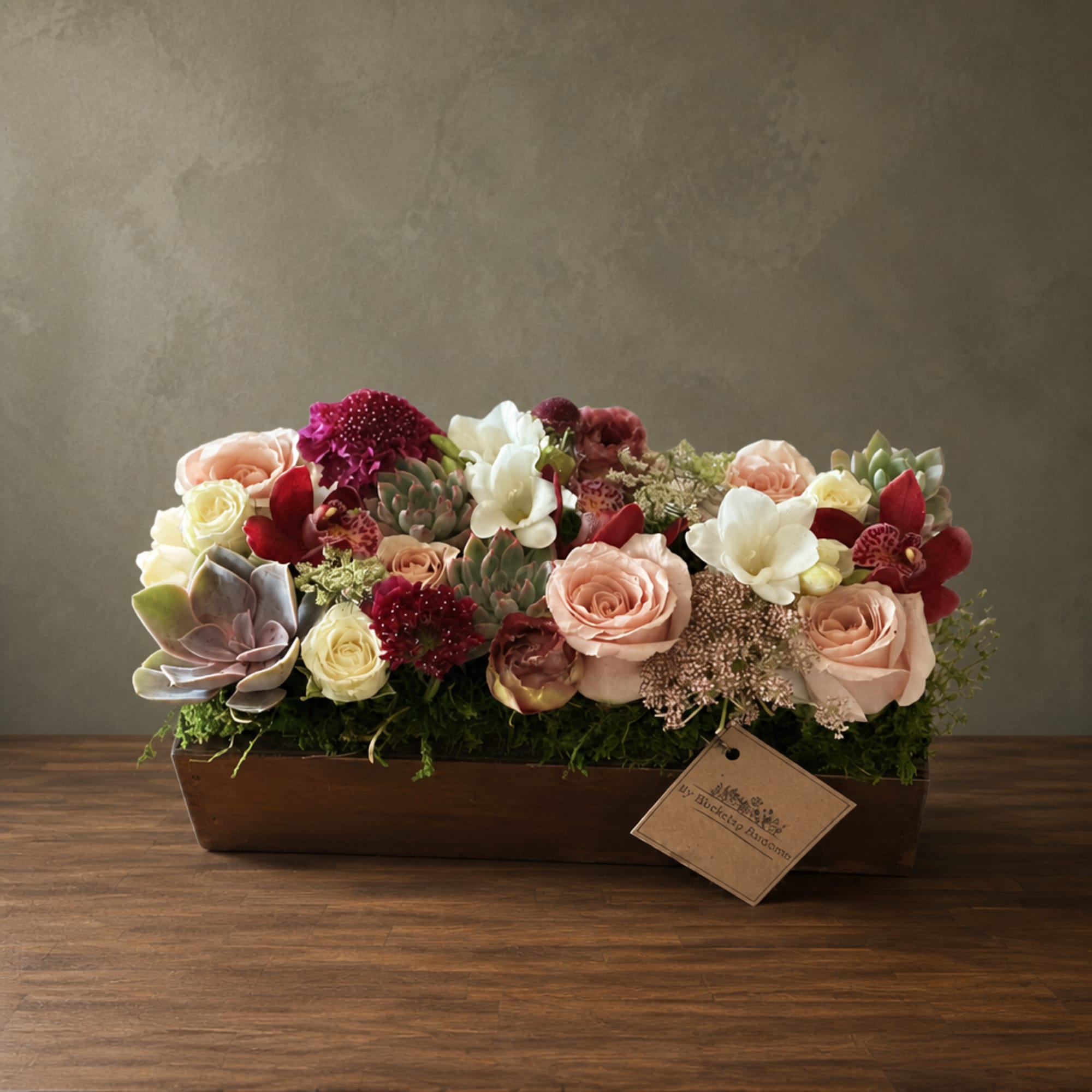 Mixed floral arrangement in a rectangular wooden box with roses and succulents