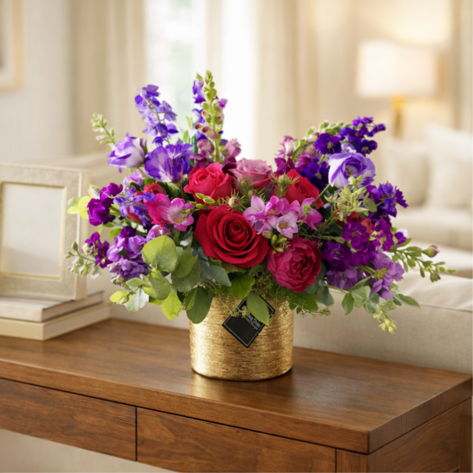Bouquet of red roses and purple flowers in a gold vase