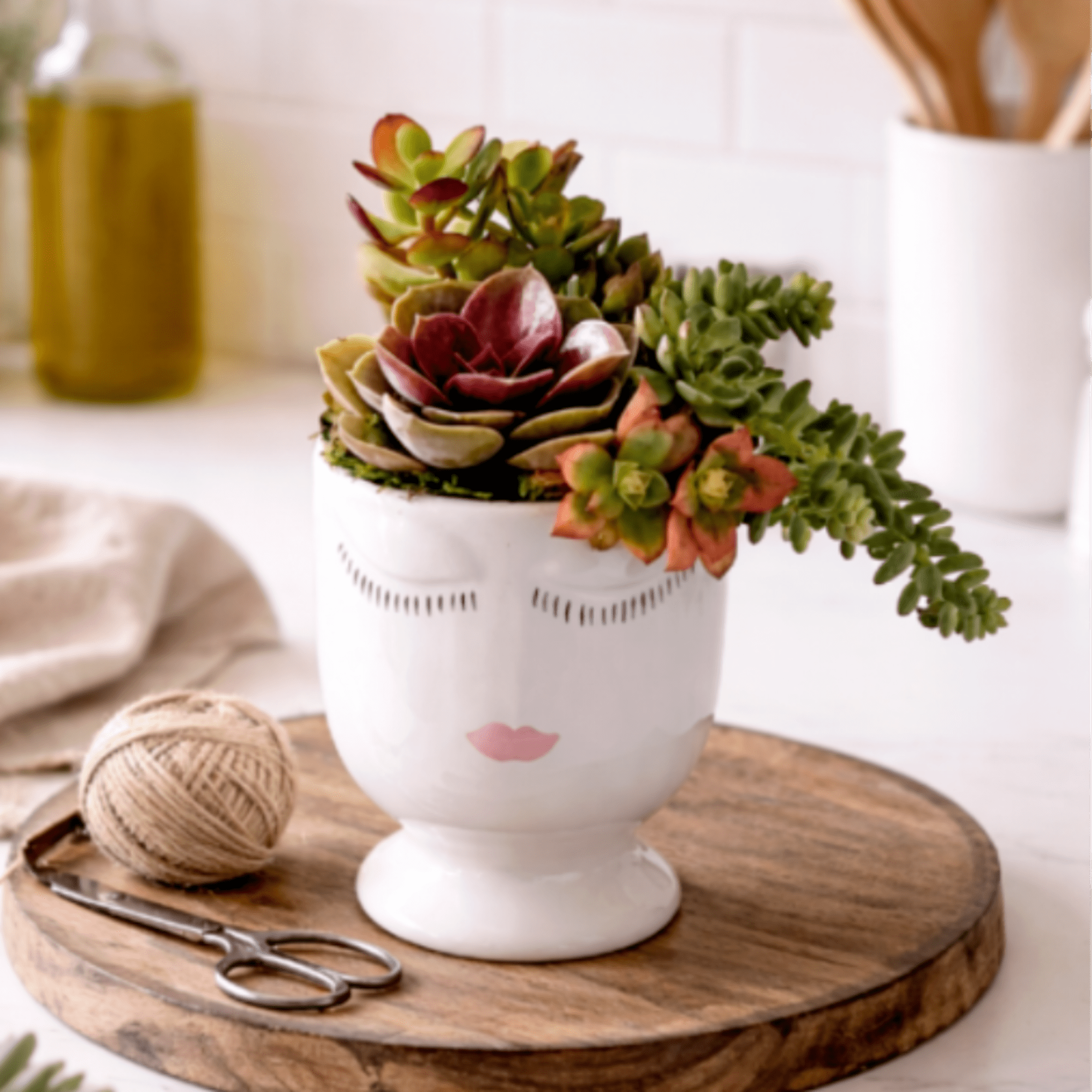 Succulent arrangement in a white face-shaped planter on a wooden tray
