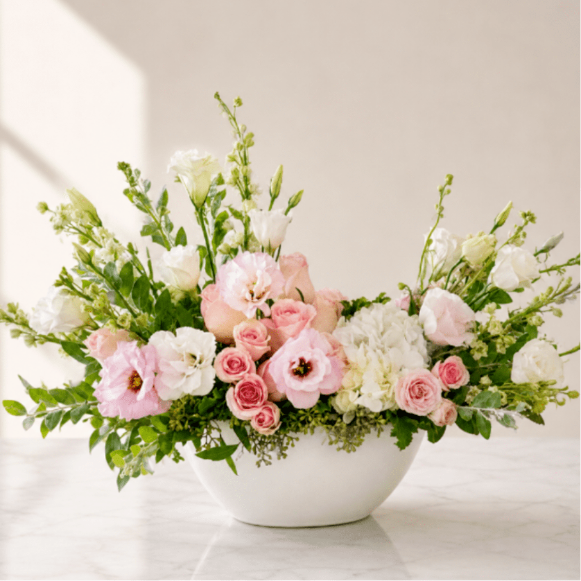 Pink and white floral arrangement in a white bowl vase