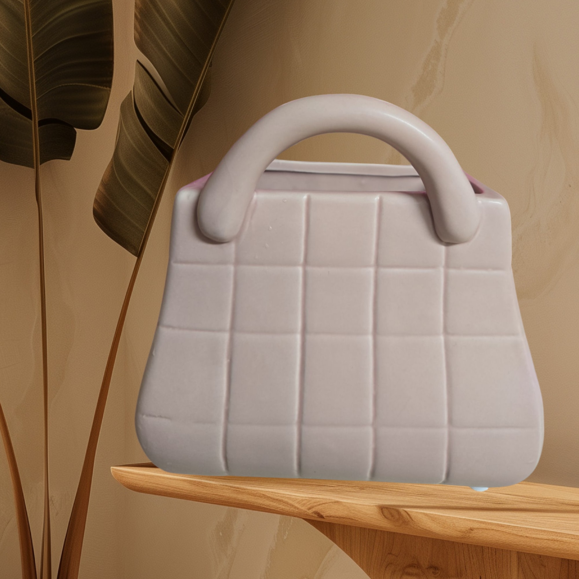 White quilted handbag on a wooden table beside tall leaves