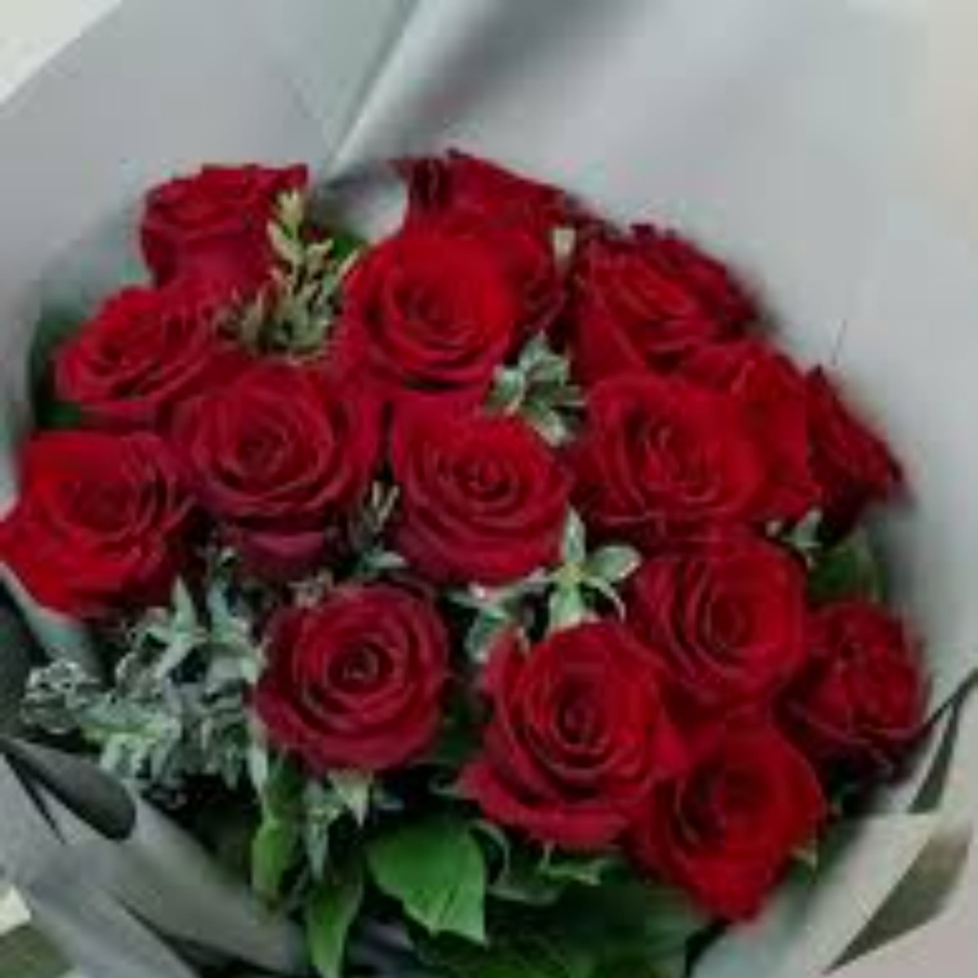 Bouquet of red roses wrapped in pale paper