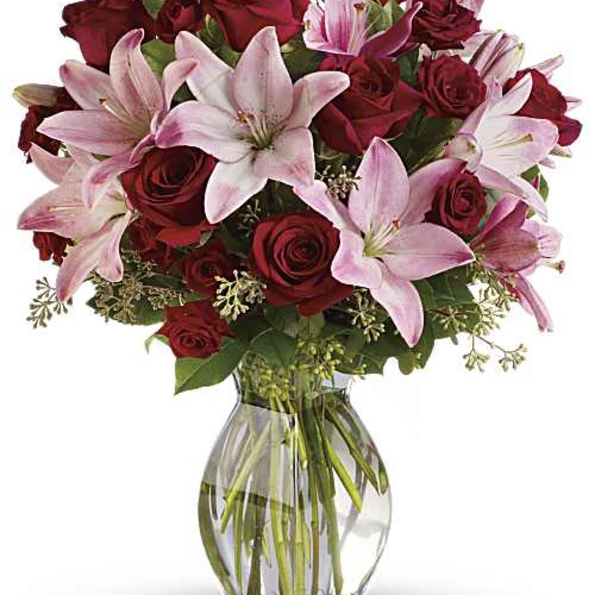 Arrangement of red roses and pink lilies in a clear glass vase filled with water.
