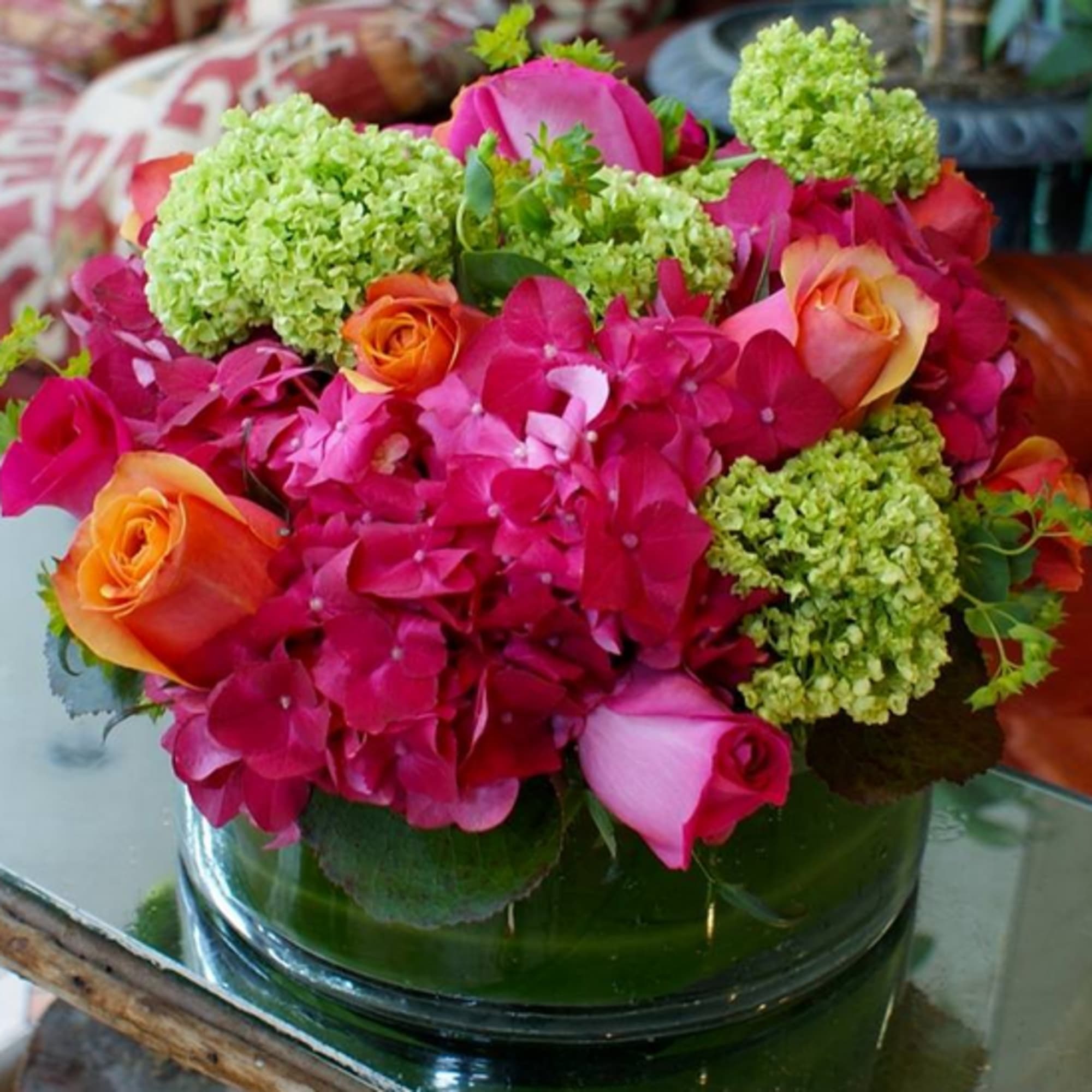 Pink hydrangeas and orange roses in a low glass vase