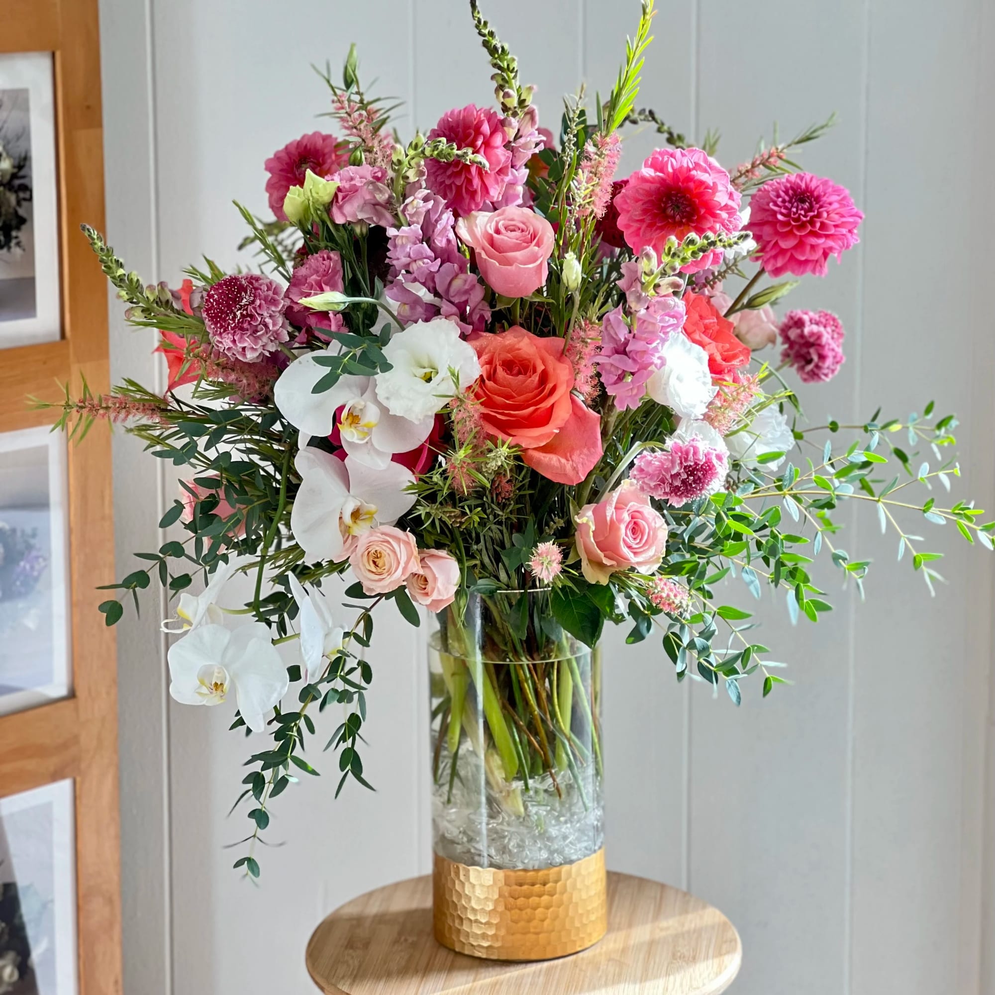 Tall mixed bouquet of pink, white, and coral flowers in a glass vase