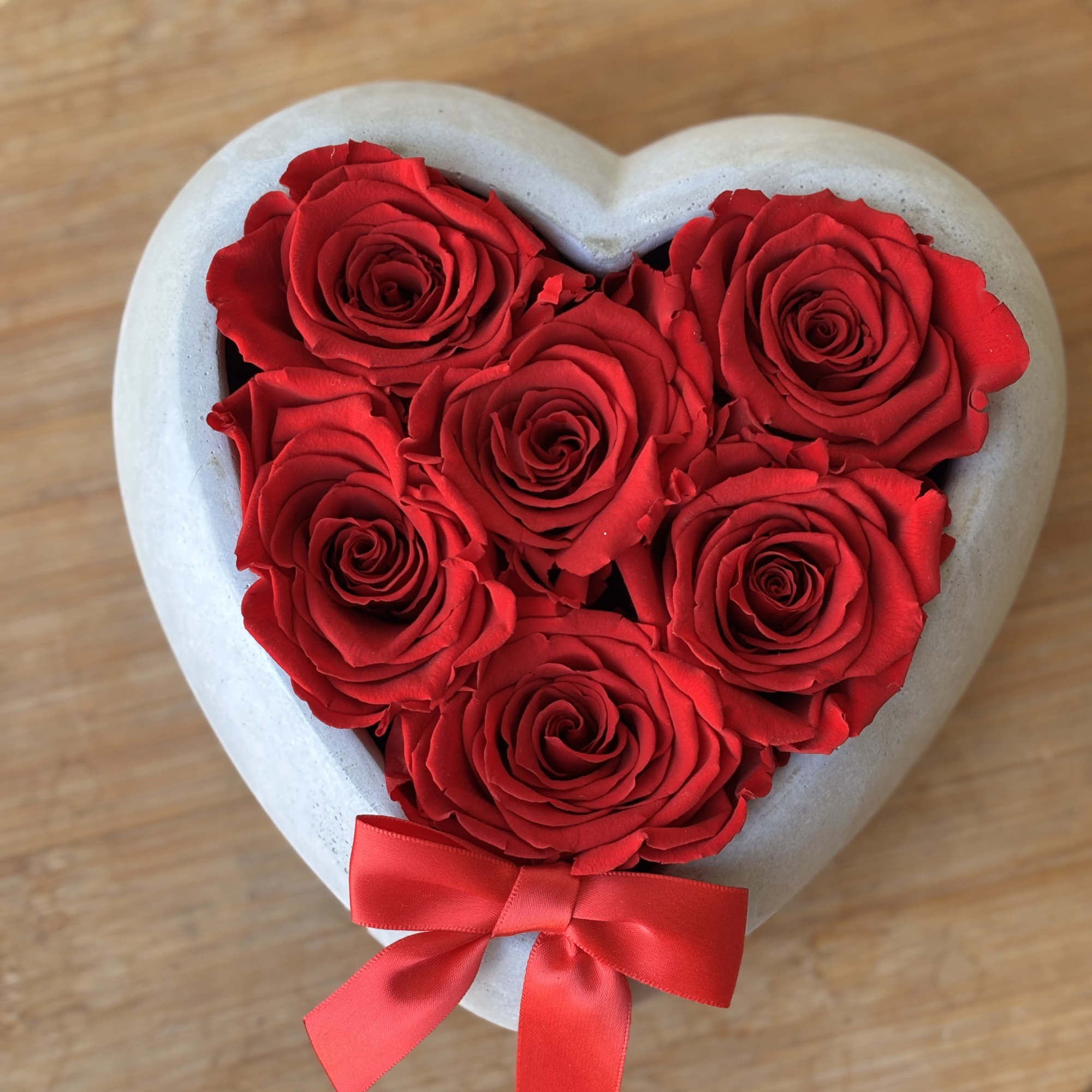 Heart-shaped box filled with red roses and a red ribbon bow