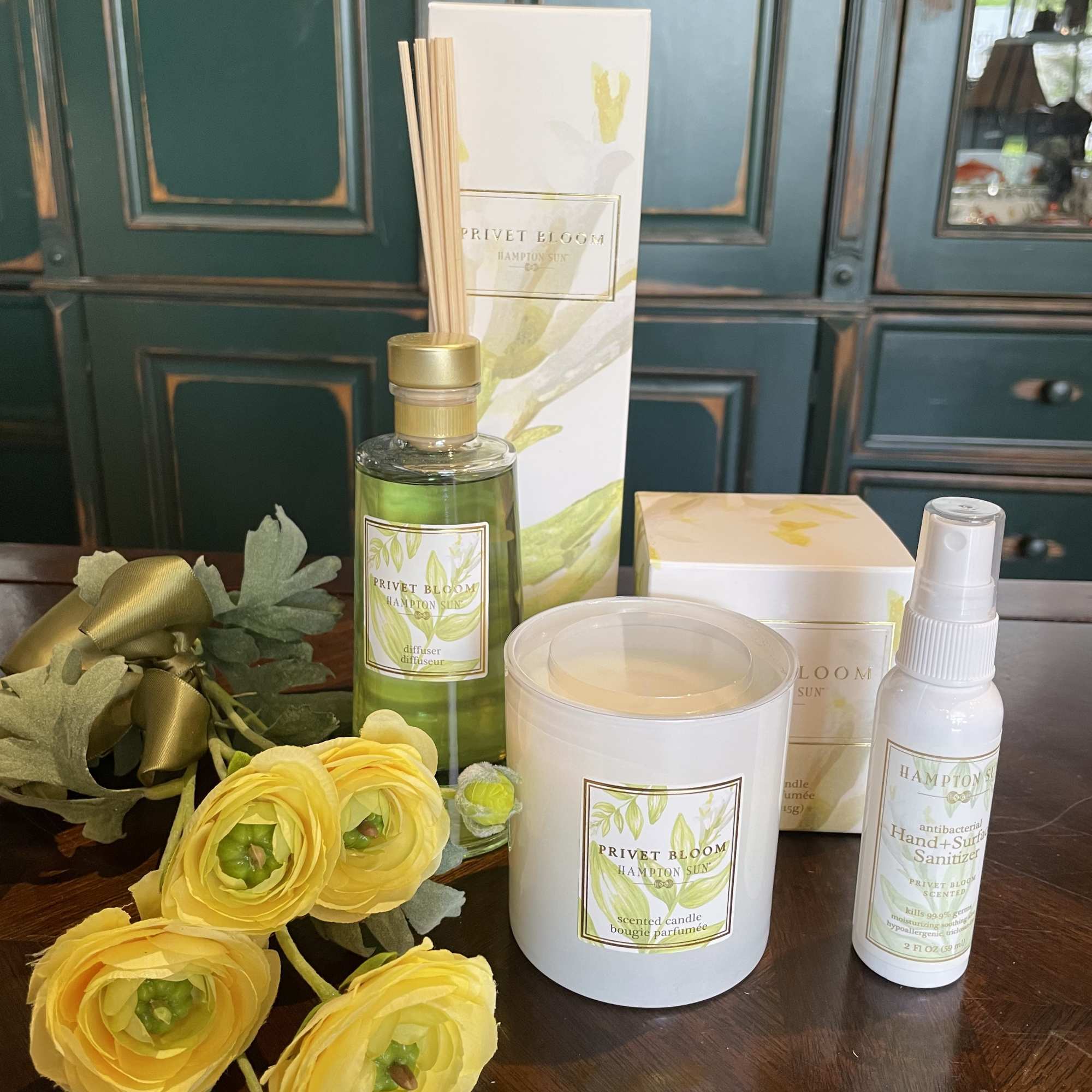 Yellow ranunculus stems with a candle, diffuser, and sanitizer gift set