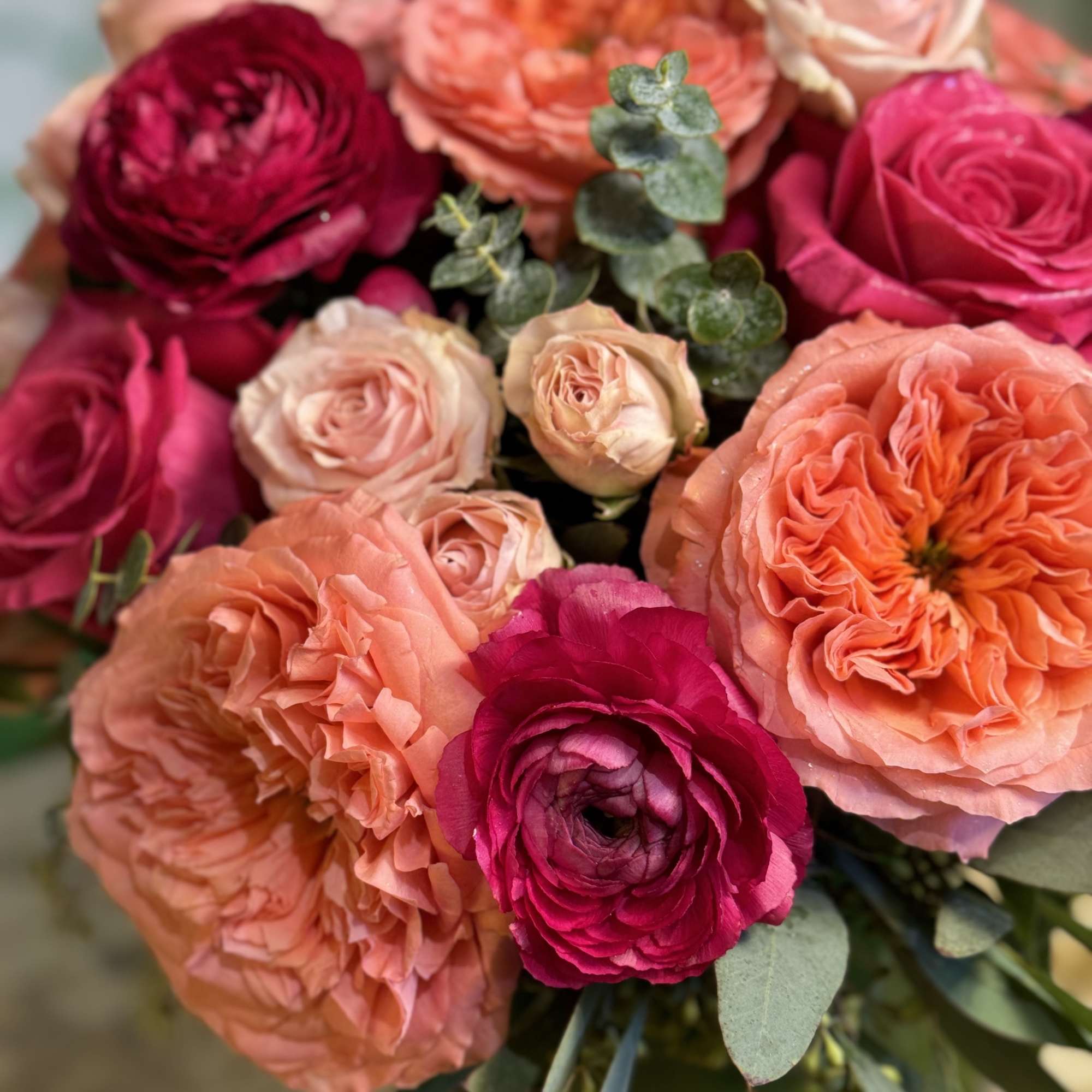Bouquet of pink, peach, and burgundy roses with eucalyptus