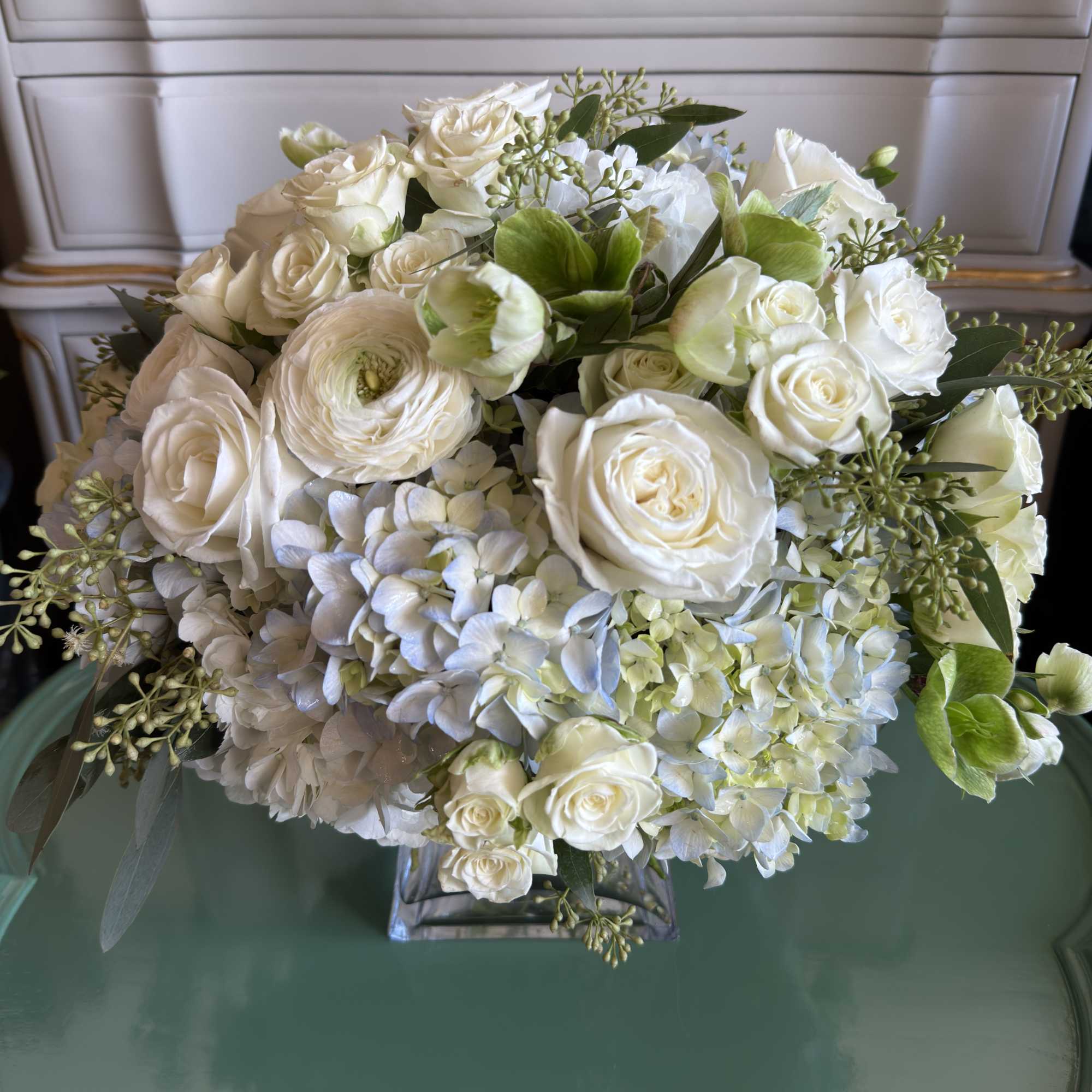 White roses and pale blue hydrangeas in a glass vase