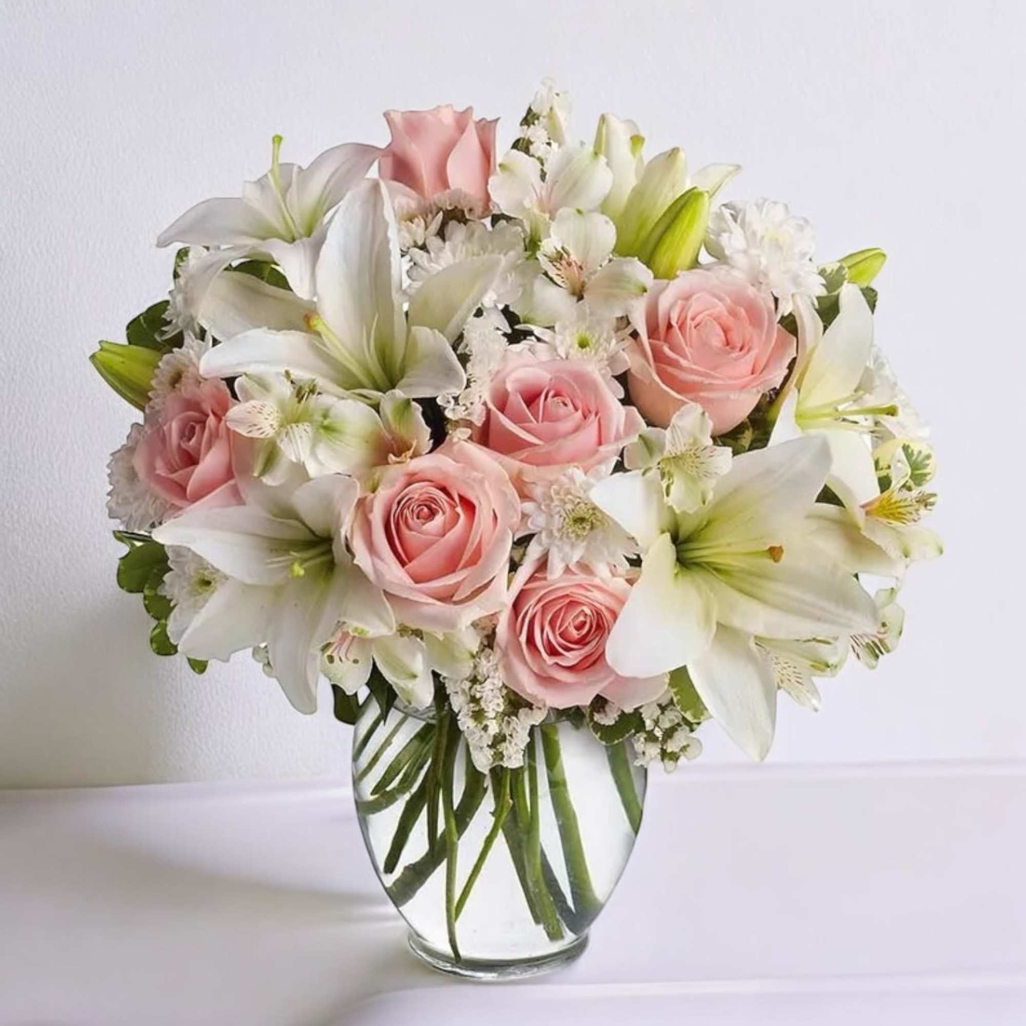 Pink roses and white lilies arranged in a clear glass vase