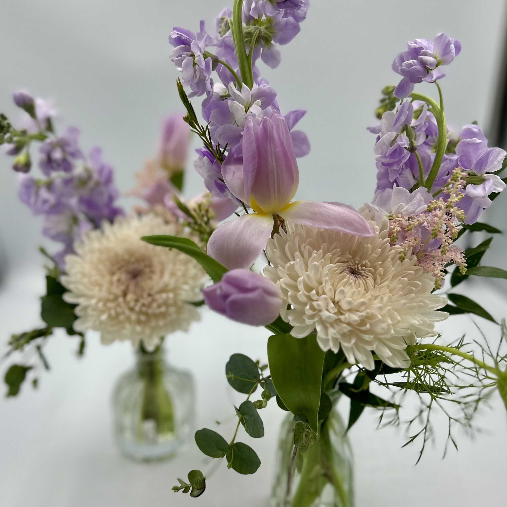 Lavender and white flowers arranged in small glass vases