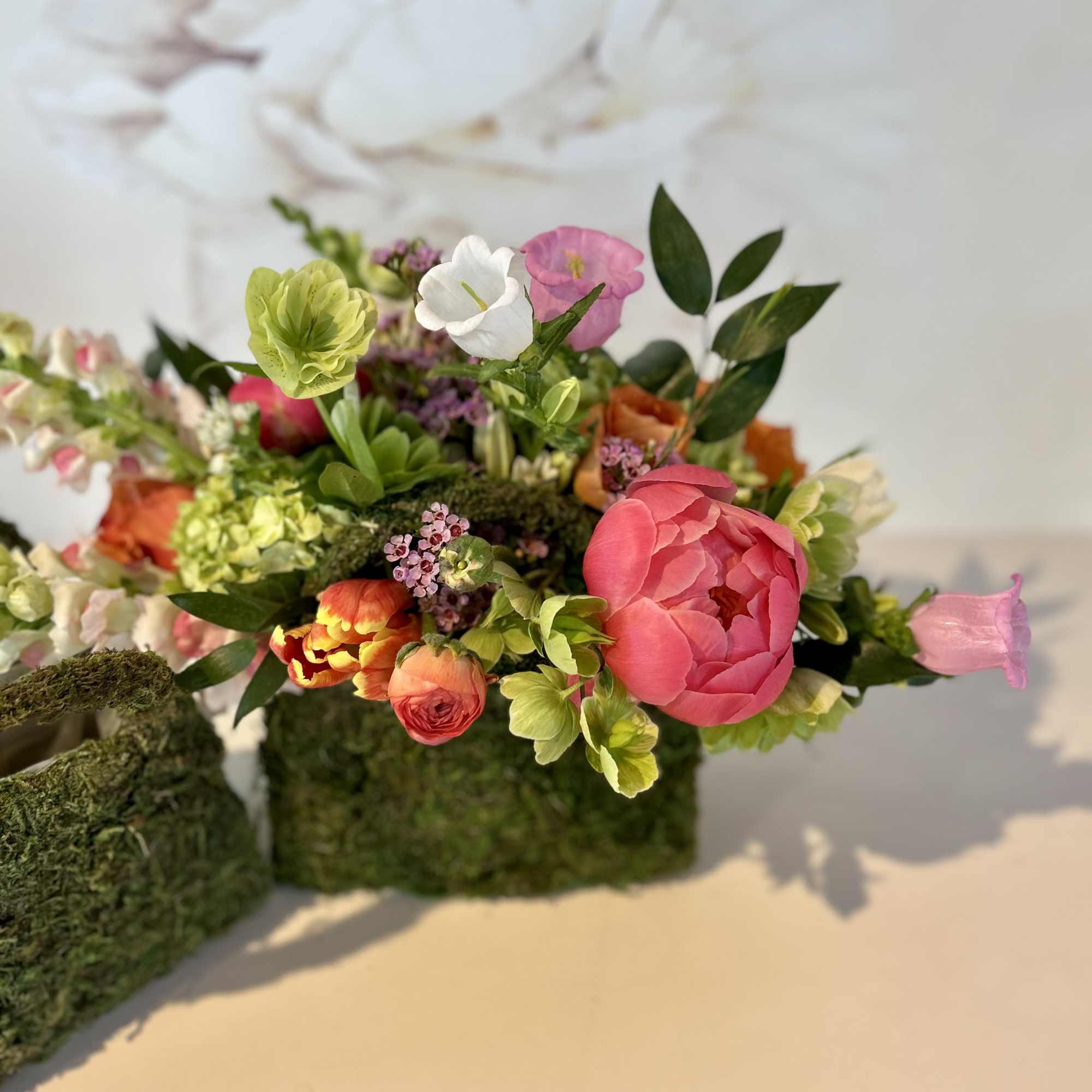 Colorful floral arrangement with pink, white, and orange blooms in a moss base