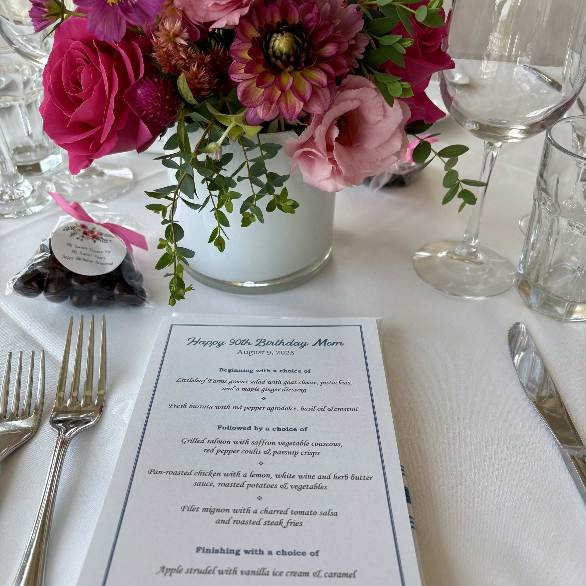 Pink and purple floral centerpiece in a white vase on a set dining table