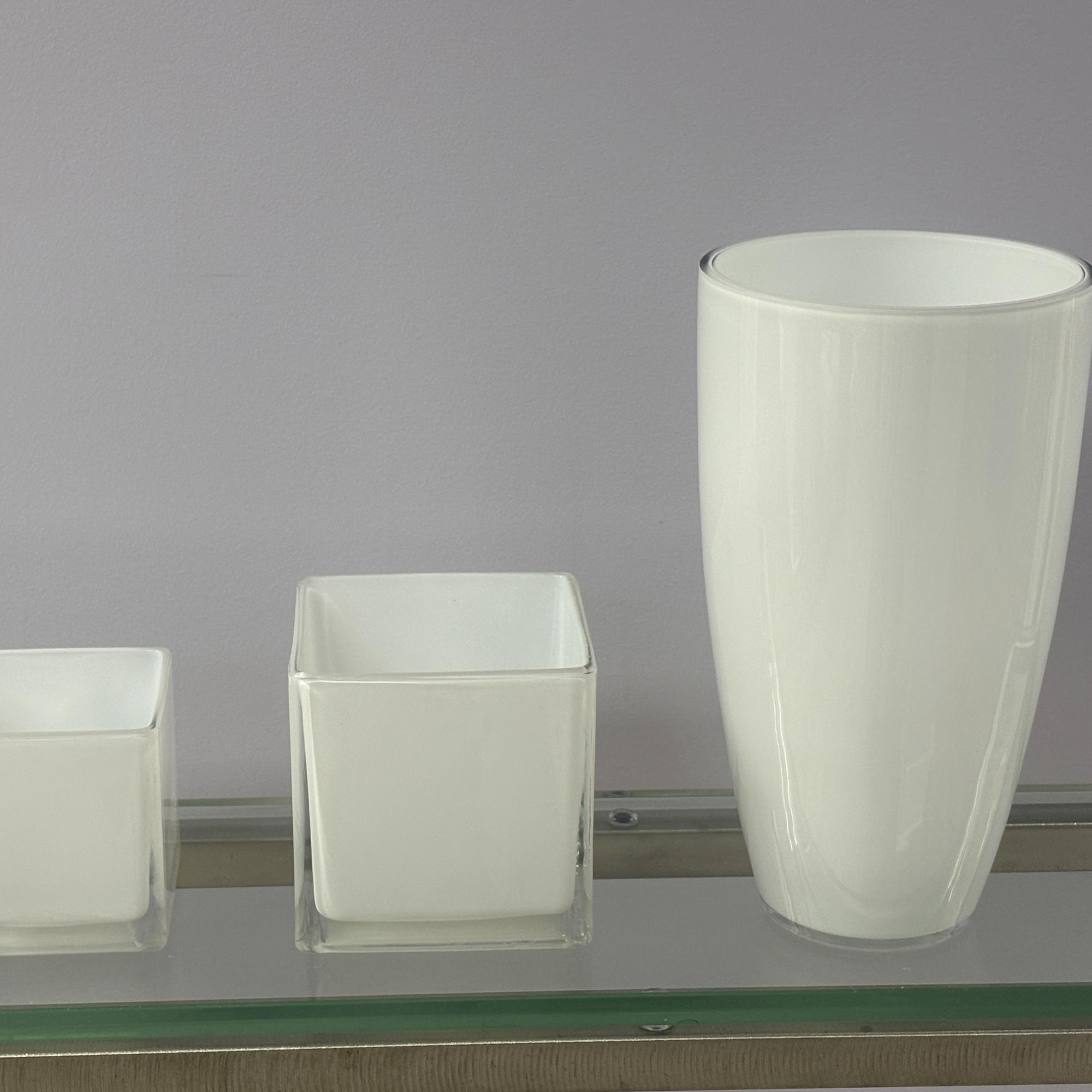 Three white glass vases in different sizes on a shelf