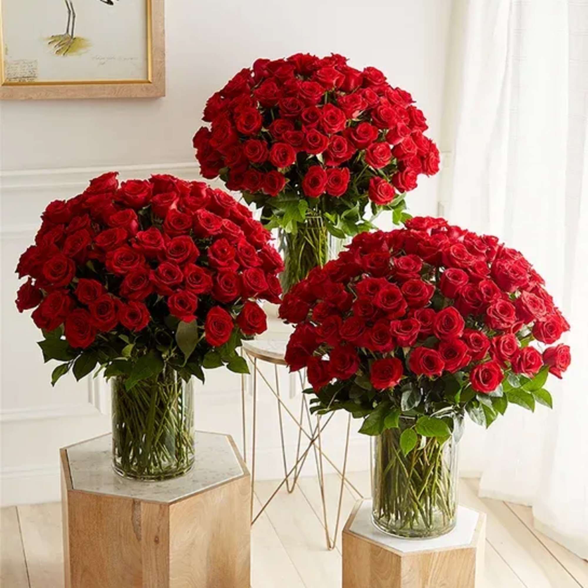 Three large bouquets of red roses in clear glass vases