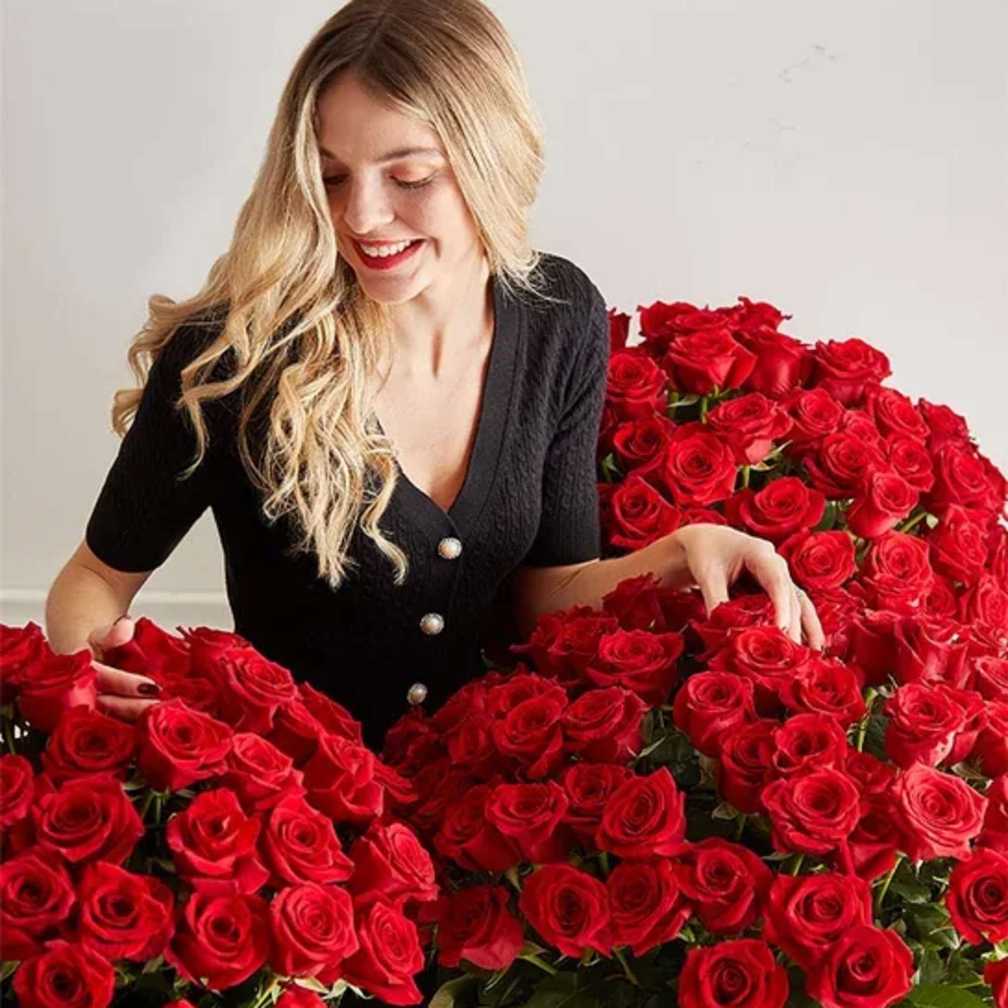 Woman surrounded by large arrangements of red roses